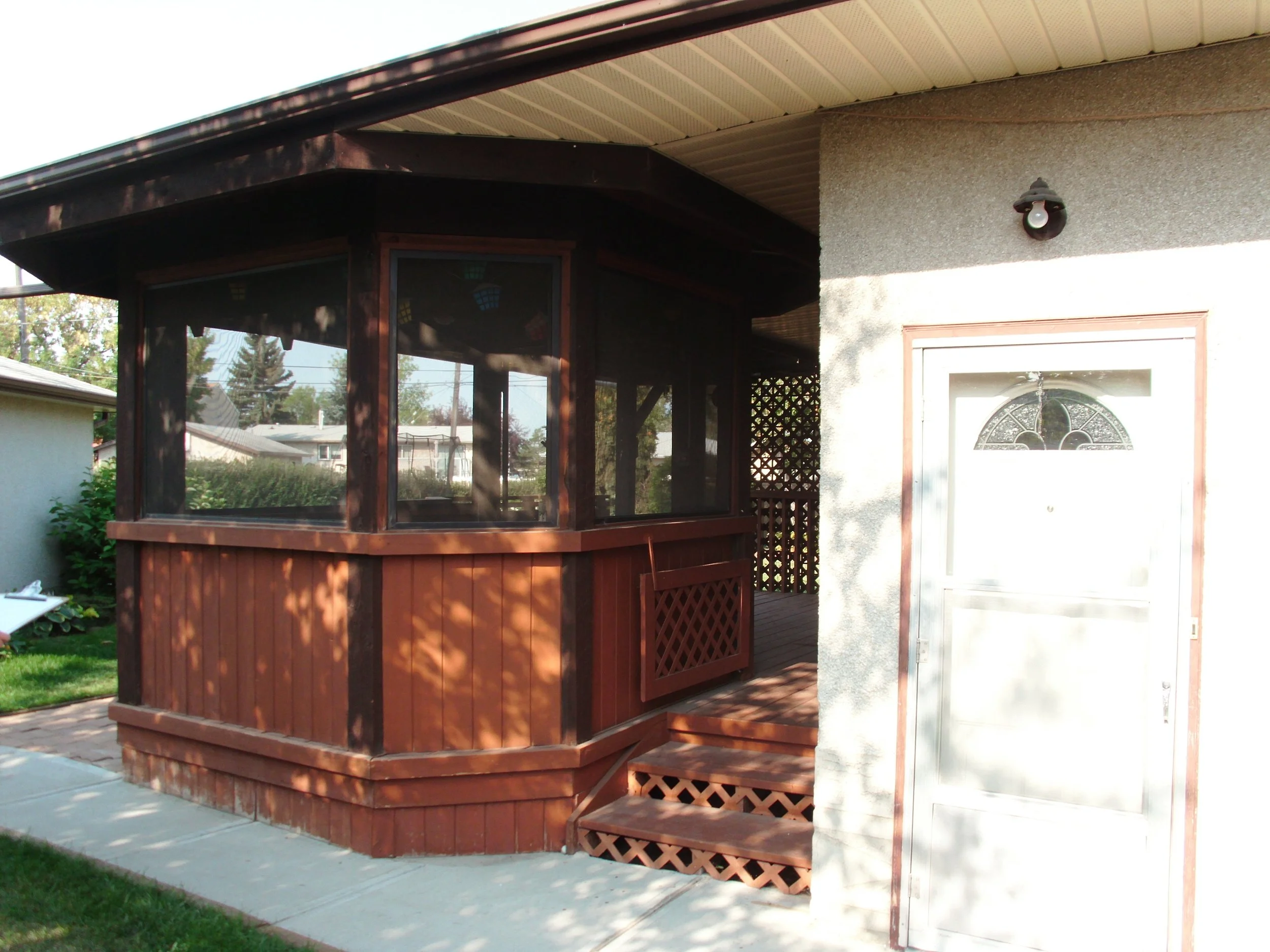Screenroom under existing house eaves, on a wood deck foundation.