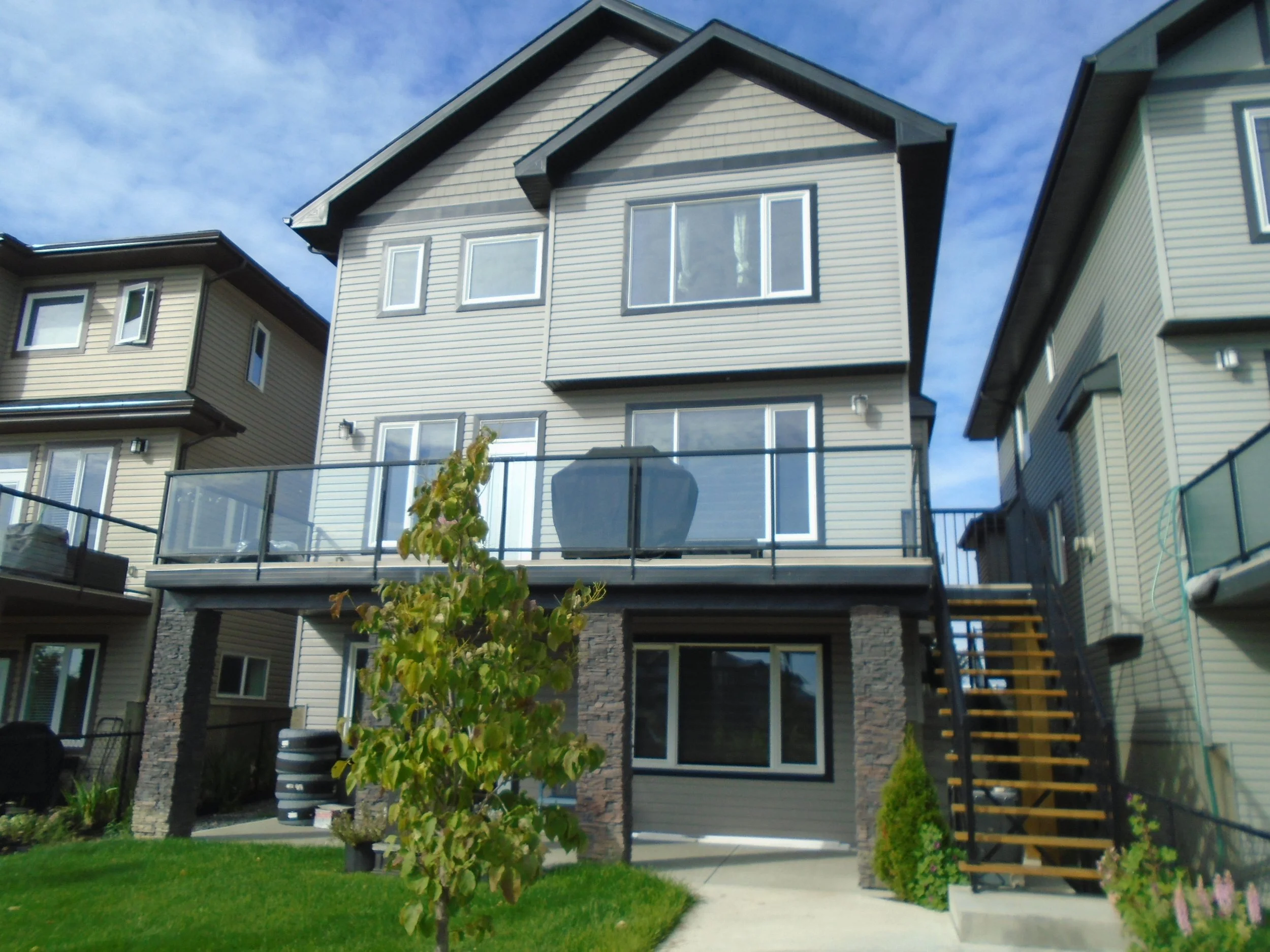 Rear wood deck, over a walk-out basement with glass handrail and guardrail.