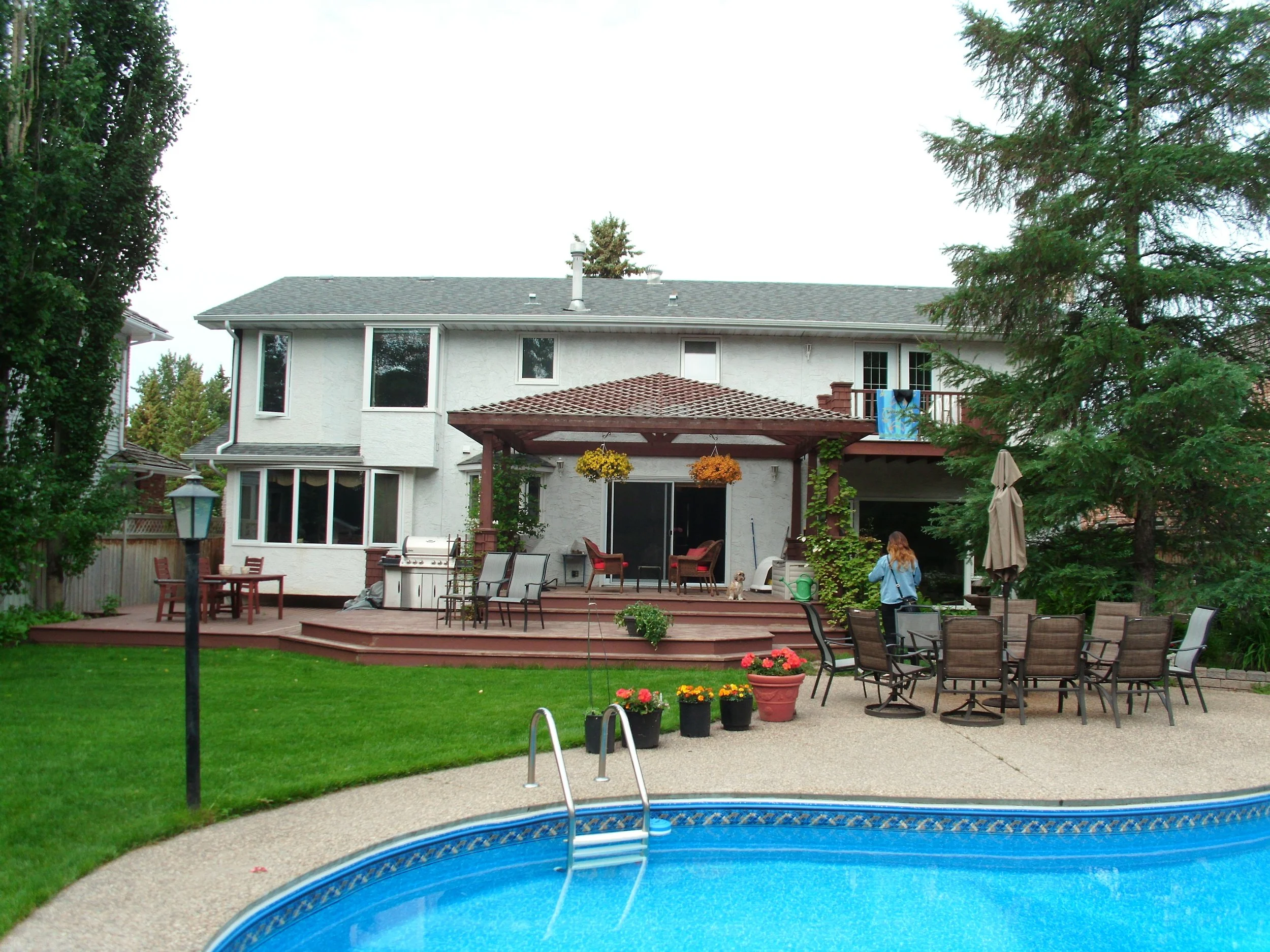 Backyard with wood pergola on deck and pool.