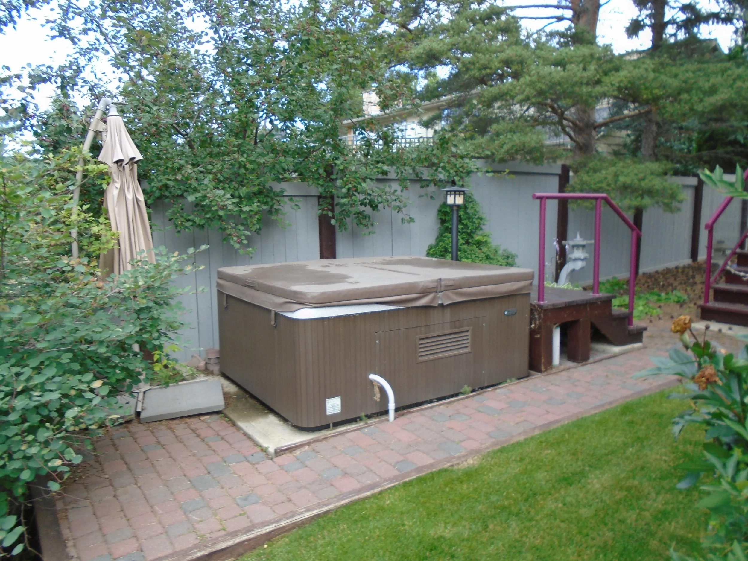 Hot tub with lid located on paving stones.