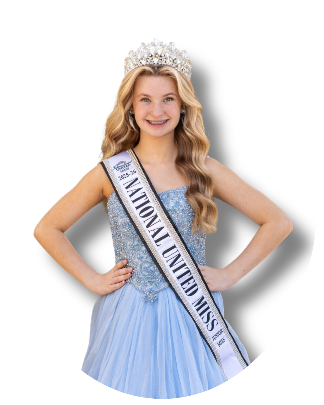 Young woman wearing a blue evening gown, a sash labeled 'National United Miss 2025-26,' and a sparkling tiara, smiling with hands on her hips.