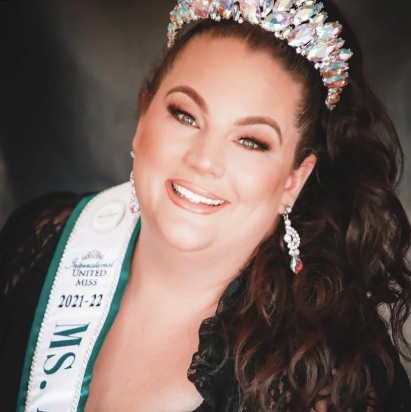 A woman wearing a tiara and earrings, smiling, with a sash indicating she is Miss Vermont 2021-22.