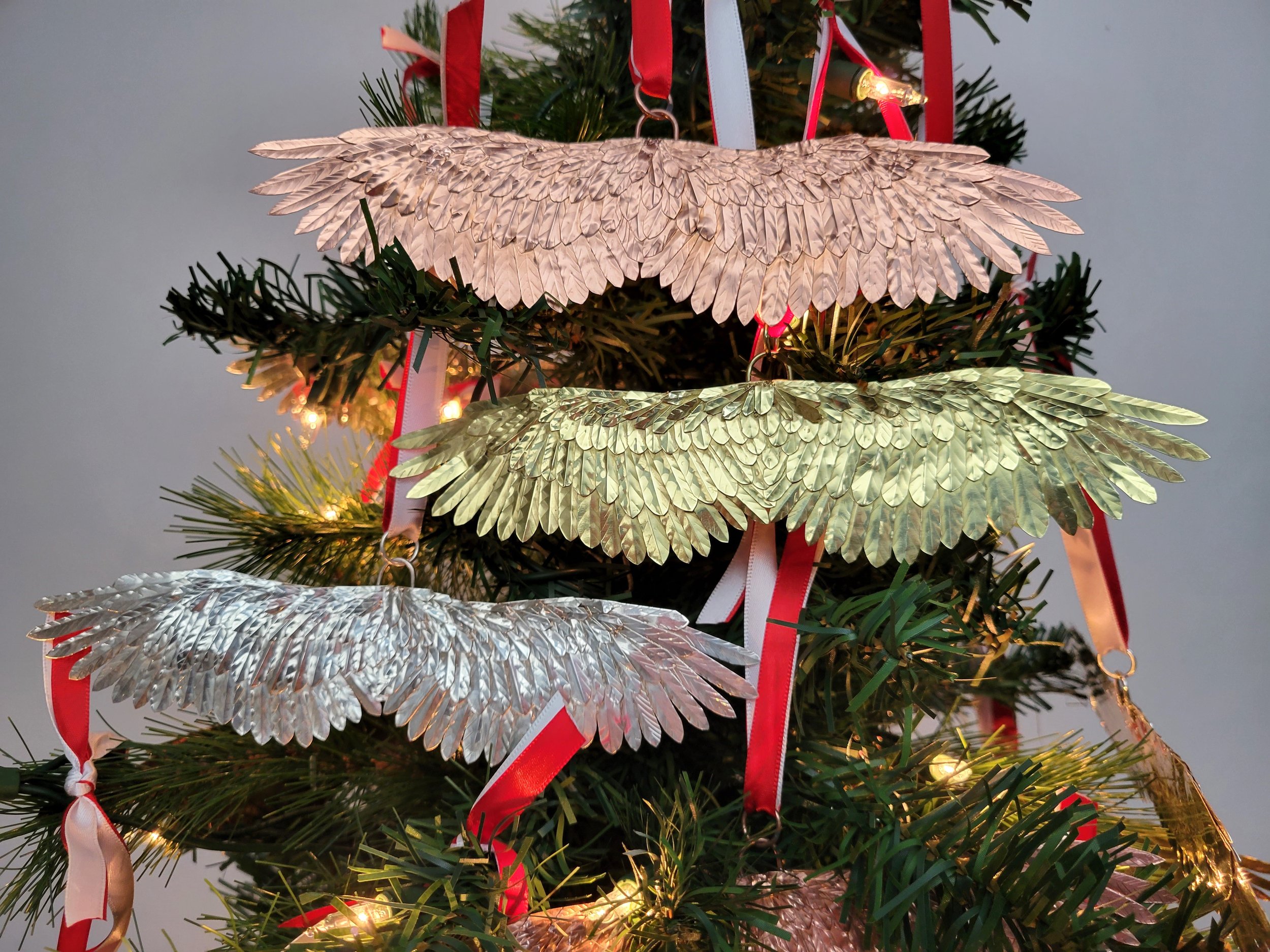 Handmade 2023 copper Christmas ornament in tree with sterling silver and brass wings.