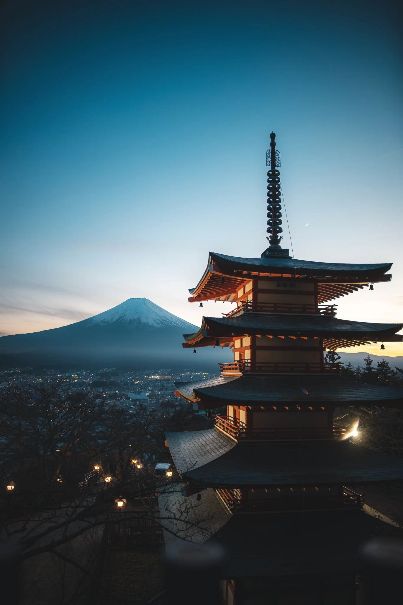 A traditional Japanese pagoda in front of Mount Fuji during sunset with a clear sky.
