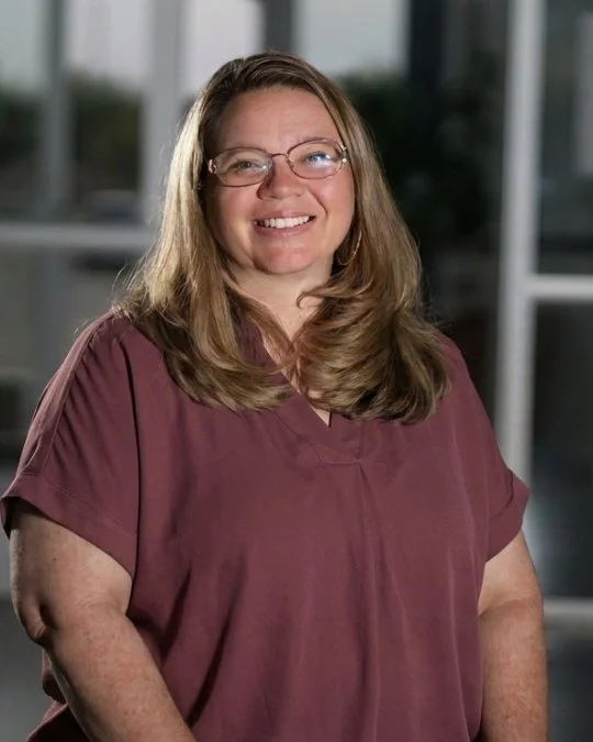 Emily Grubbs, YTH Coordinator, smiling in a studio portrait wearing a mauve blouse.