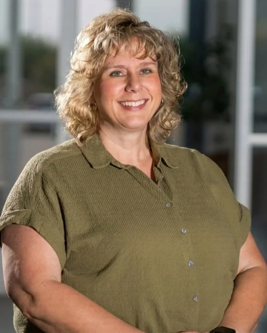 Julie Gerdes, Executive Assistant, smiling in a studio portrait wearing an olive green blouse.