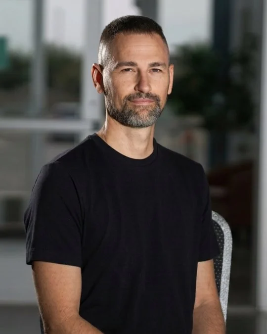 Josh Grubbs, YTH Pastor, smiling in a studio portrait wearing a black shirt.