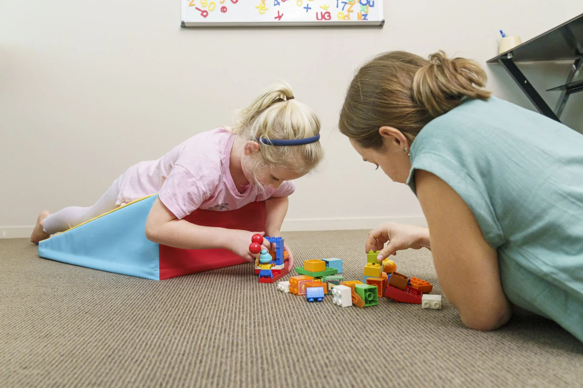 A medical professional showing a patient a knee joint model in an office setting.