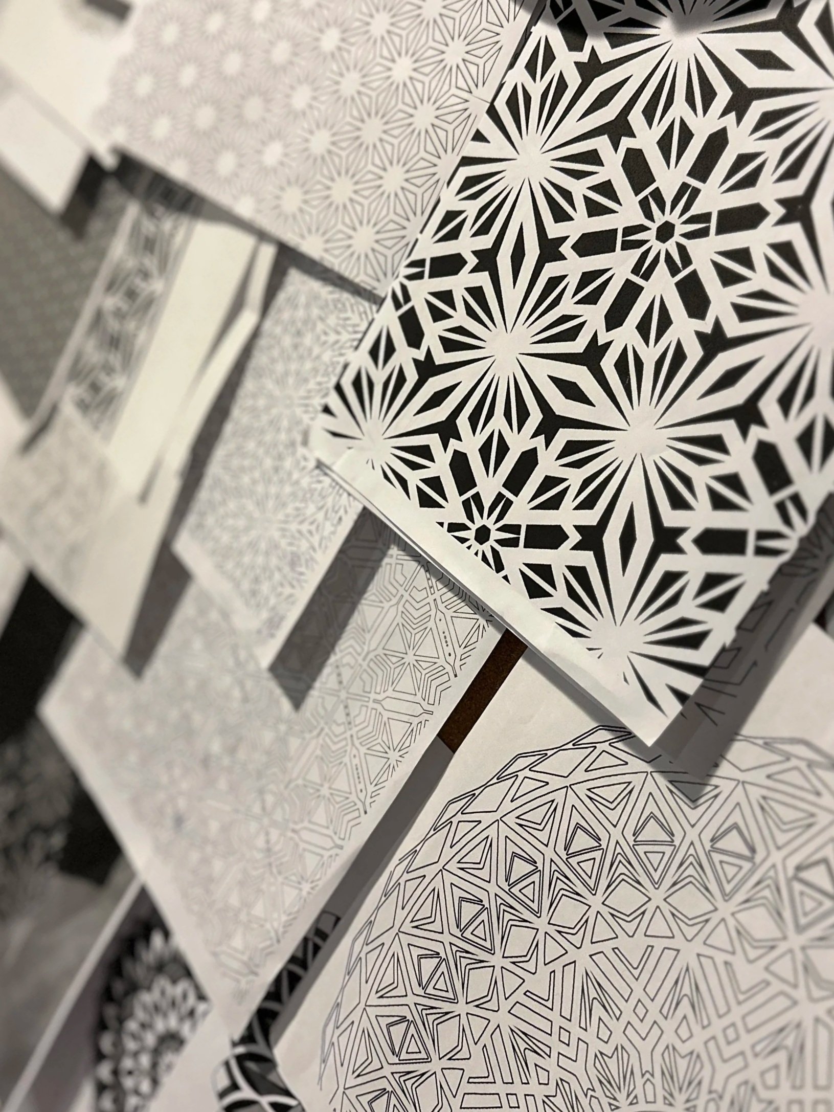 Black and white patterned printed templates with intricate geometric designs scattered on a surface.