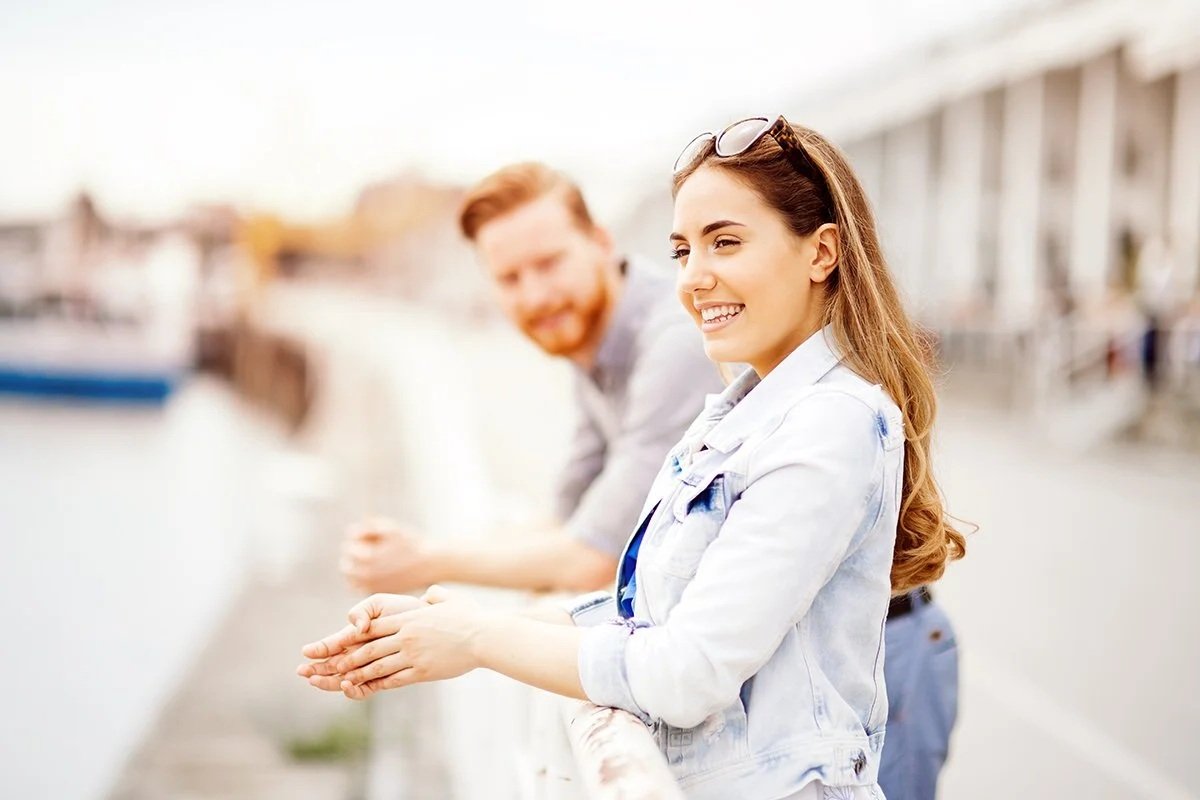 A woman smiles while engaged in relaxed conversation with a man, reflecting connection and relational ease.