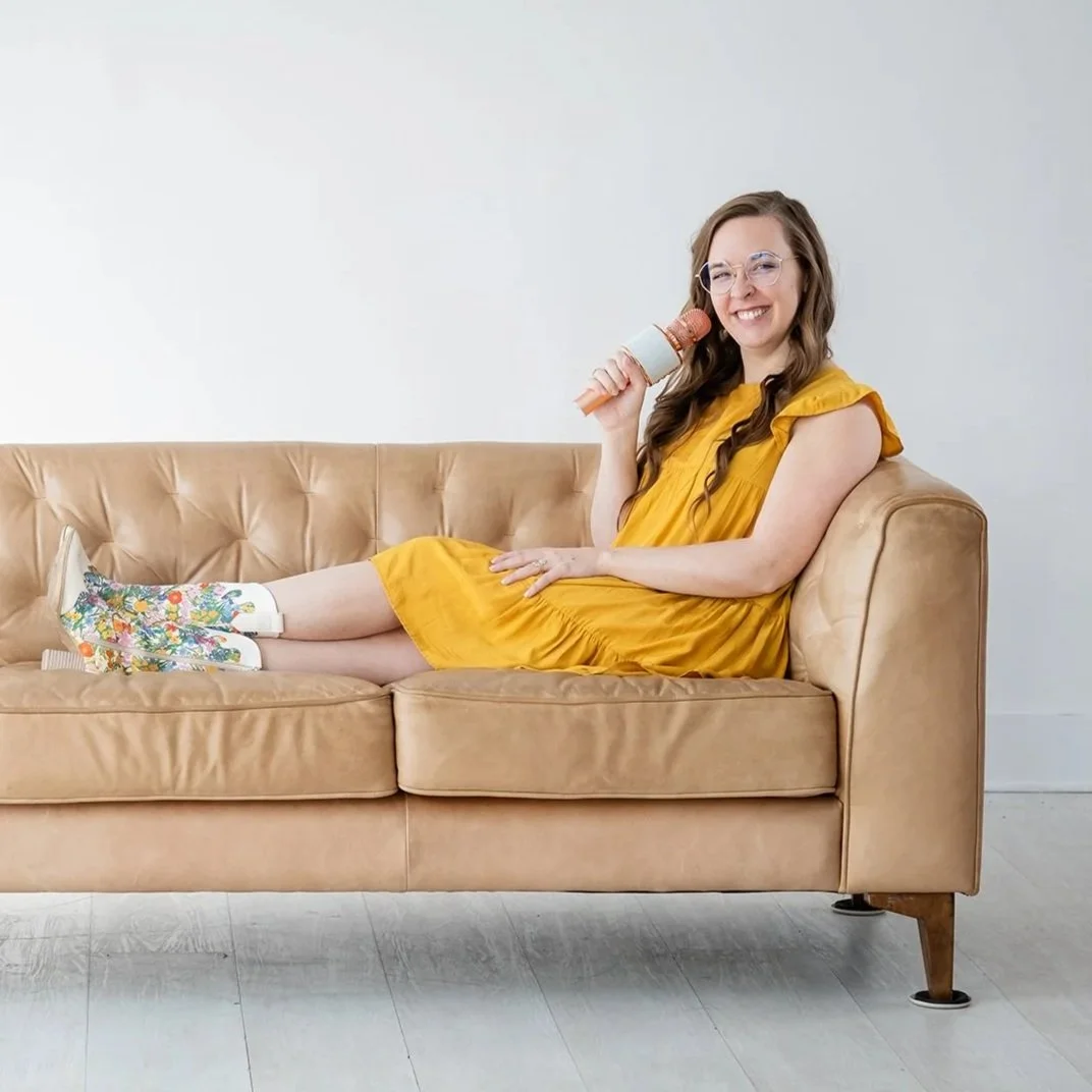 Madigan, founder of CommitmentISM, relaxes on a couch holding a microphone, inviting open questions and honest conversation.