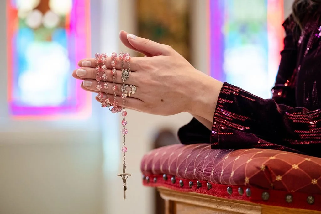 Madigan’s hands holding a rosary in prayer, representing her commitment to discernment and prayerful guidance for each match.