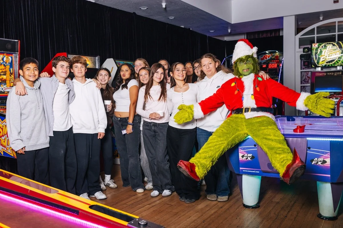 Guests posing with Grinch character entertainment at interactive arcade themed birthday celebration by Wife of the Party
