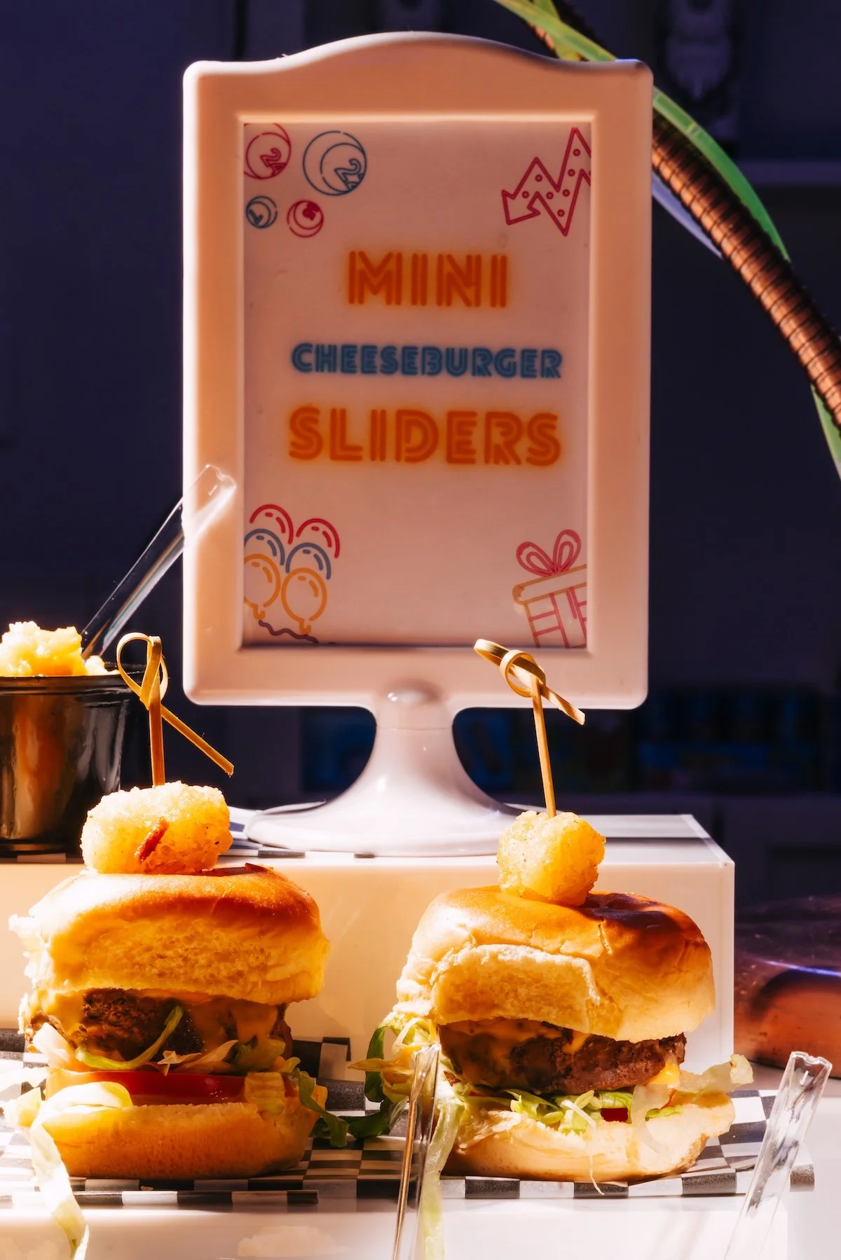 Mini cheeseburger sliders, curly fries, and mac and cheese food station at arcade themed teen birthday party by Wife of the Party