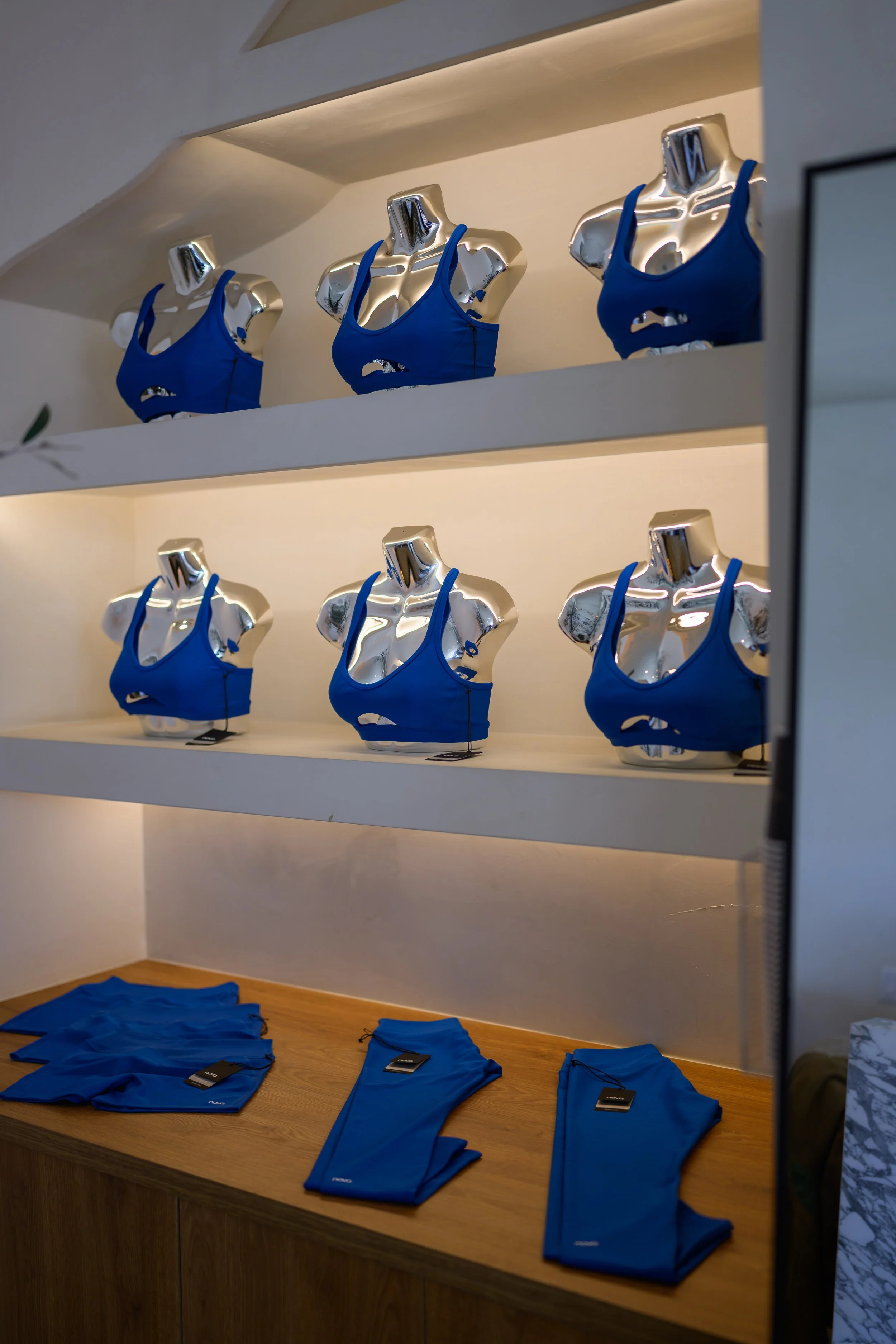 Fashion Nova Nova Fitness cobalt blue sports bras displayed on chrome mannequins in a modern luxury fitness studio designed and produced by Wife of the Party