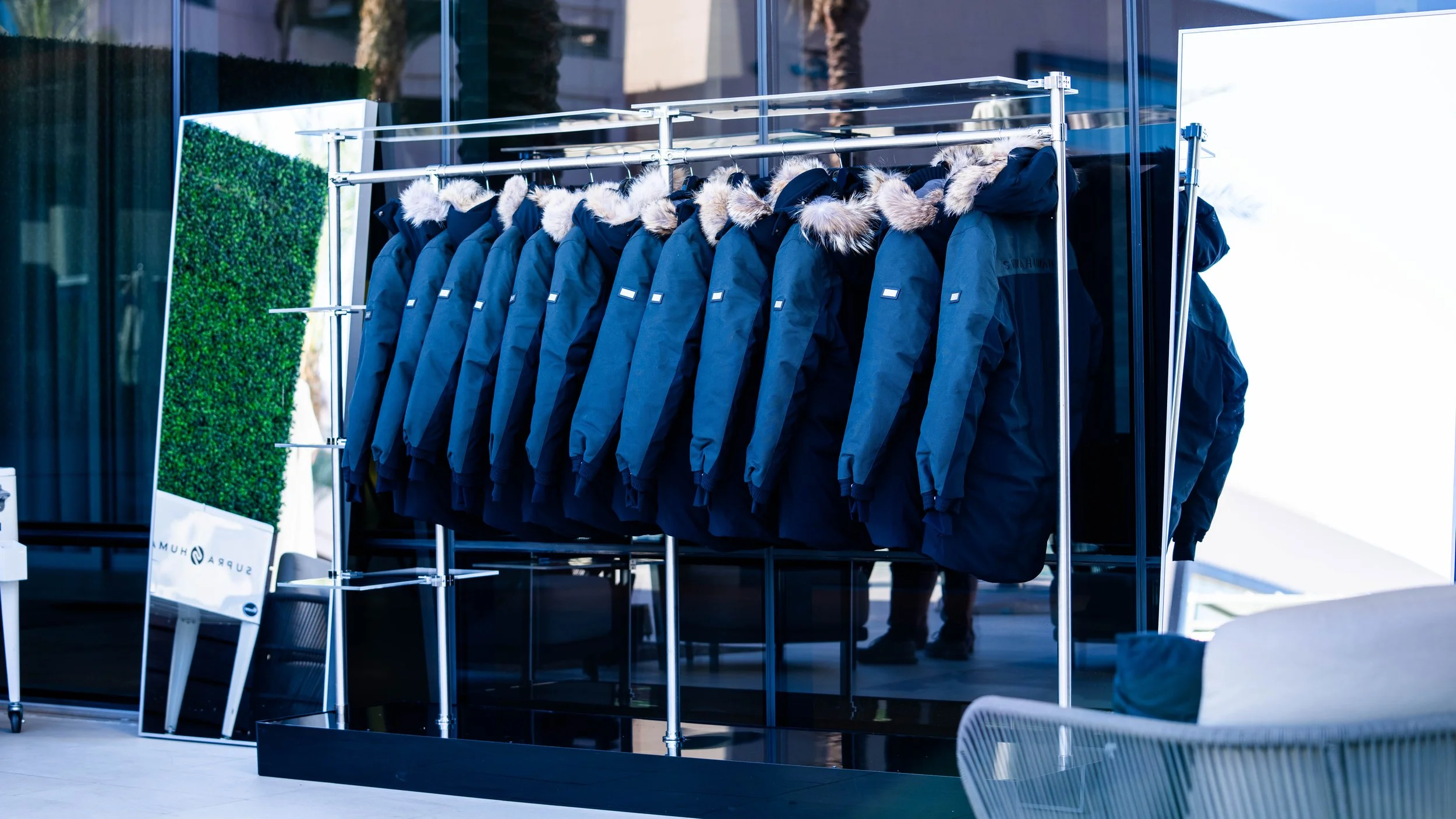 Custom guest coat display featuring luxury parkas arranged on modern racks during the Supra Human Elite Fly-In event in Scottsdale produced by Wife of the Party.