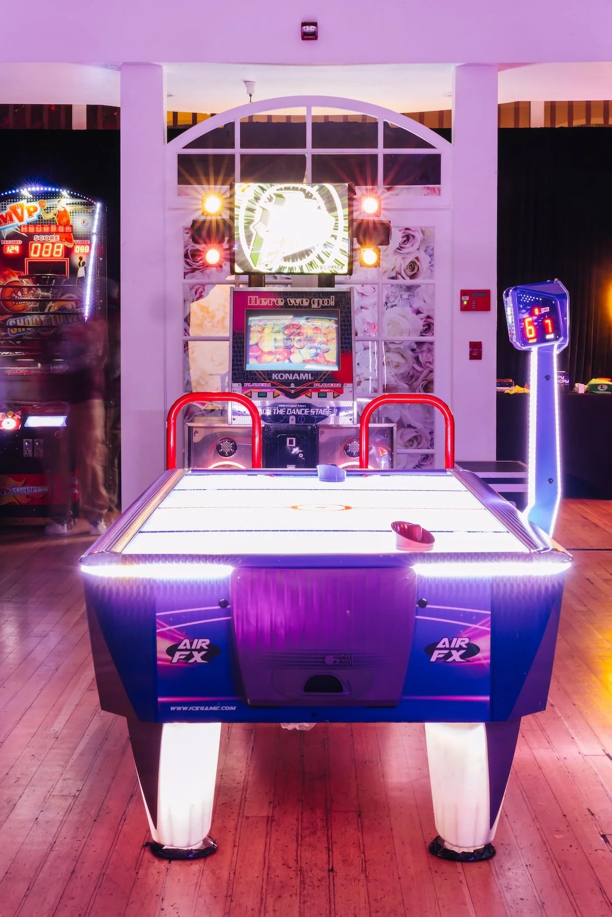 Neon arcade game setup with air hockey table and basketball shooting game at luxury teen gaming birthday party designed by Wife of the Party