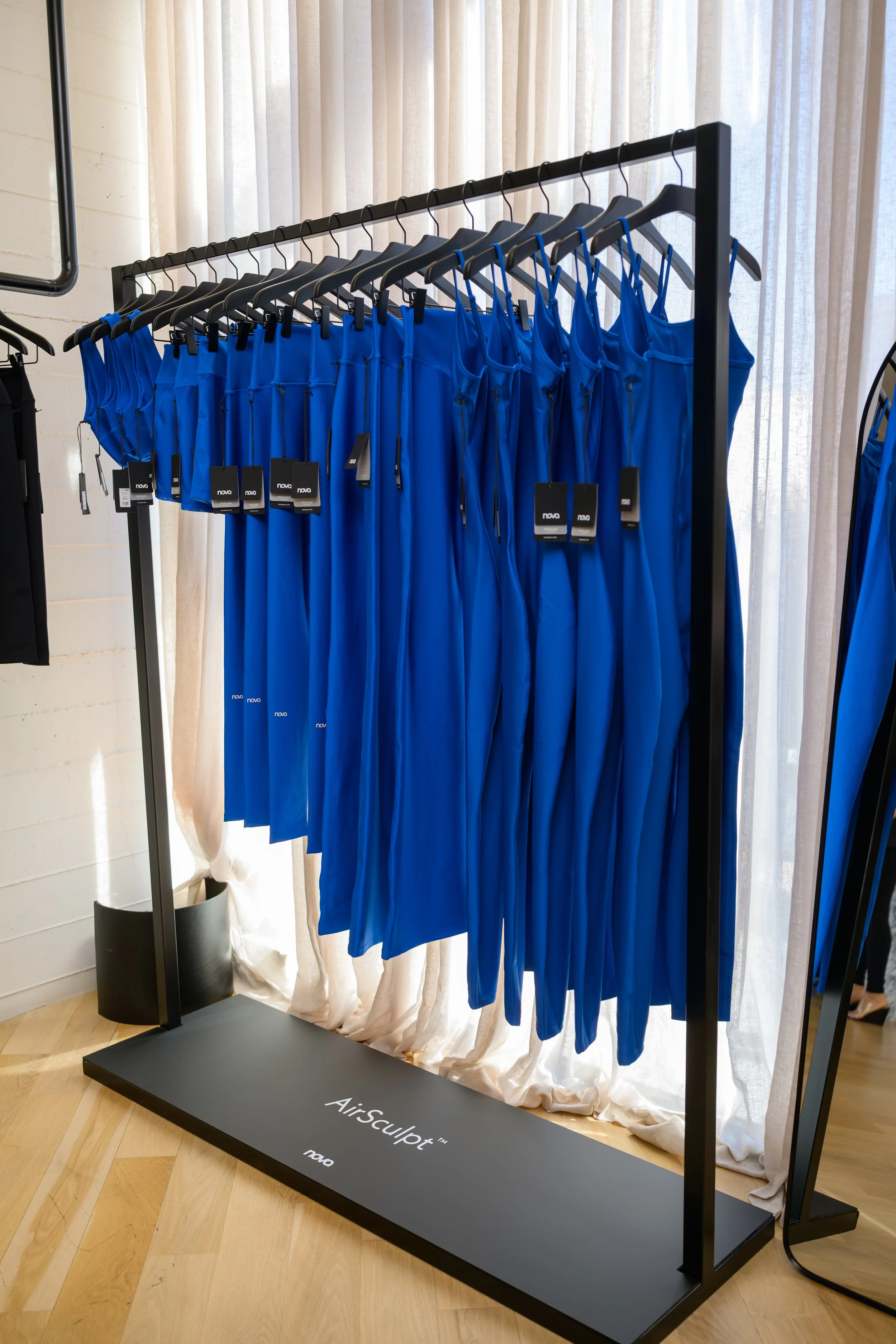 Nova Fitness apparel displayed in boutique fitness studio with Nova branded mirror and modern activewear racks at Fashion Nova launch produced by Wife of the Party