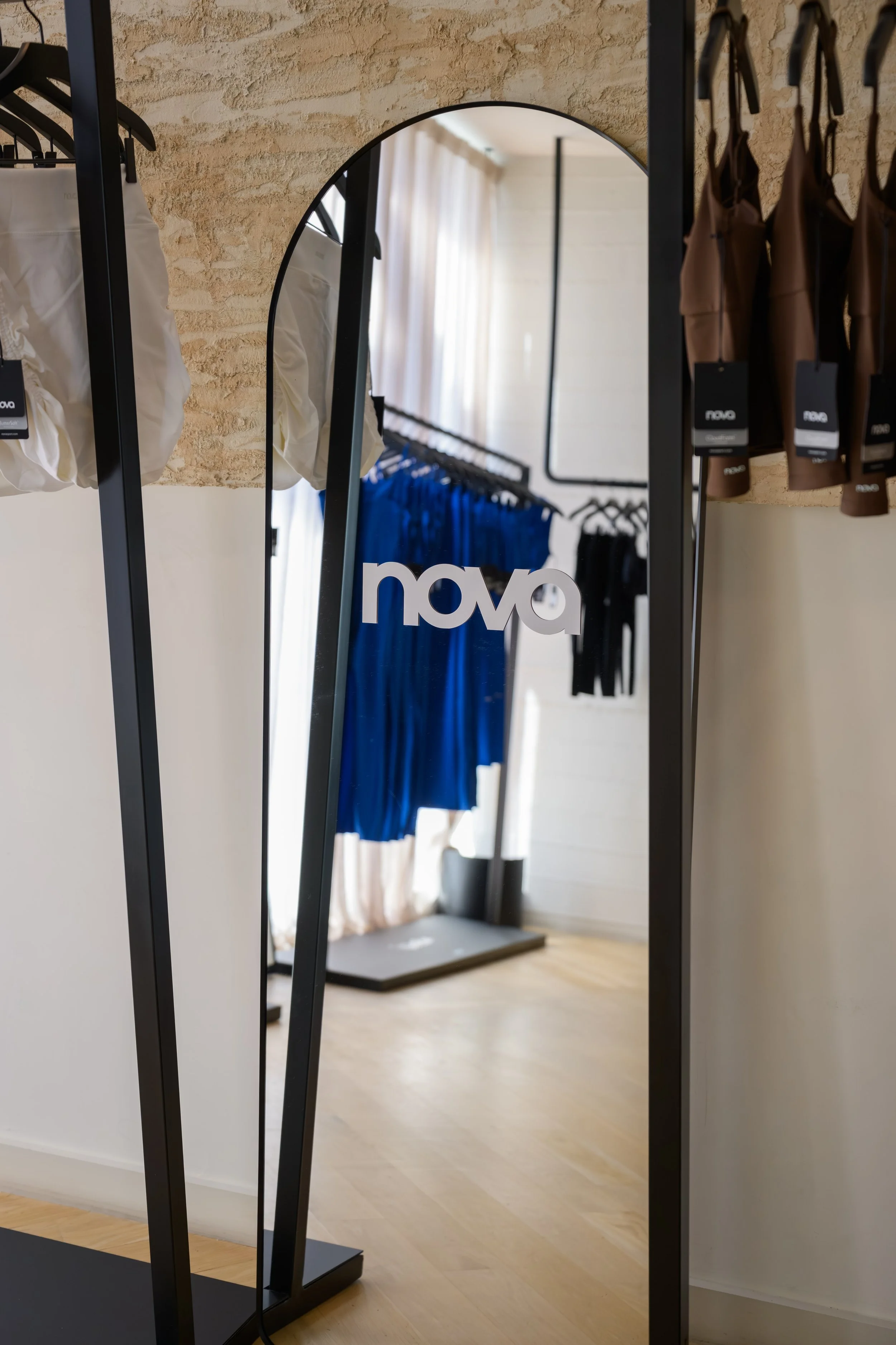 Nova Fitness apparel displayed in boutique fitness studio with Nova branded mirror and modern activewear racks at Fashion Nova launch produced by Wife of the Party