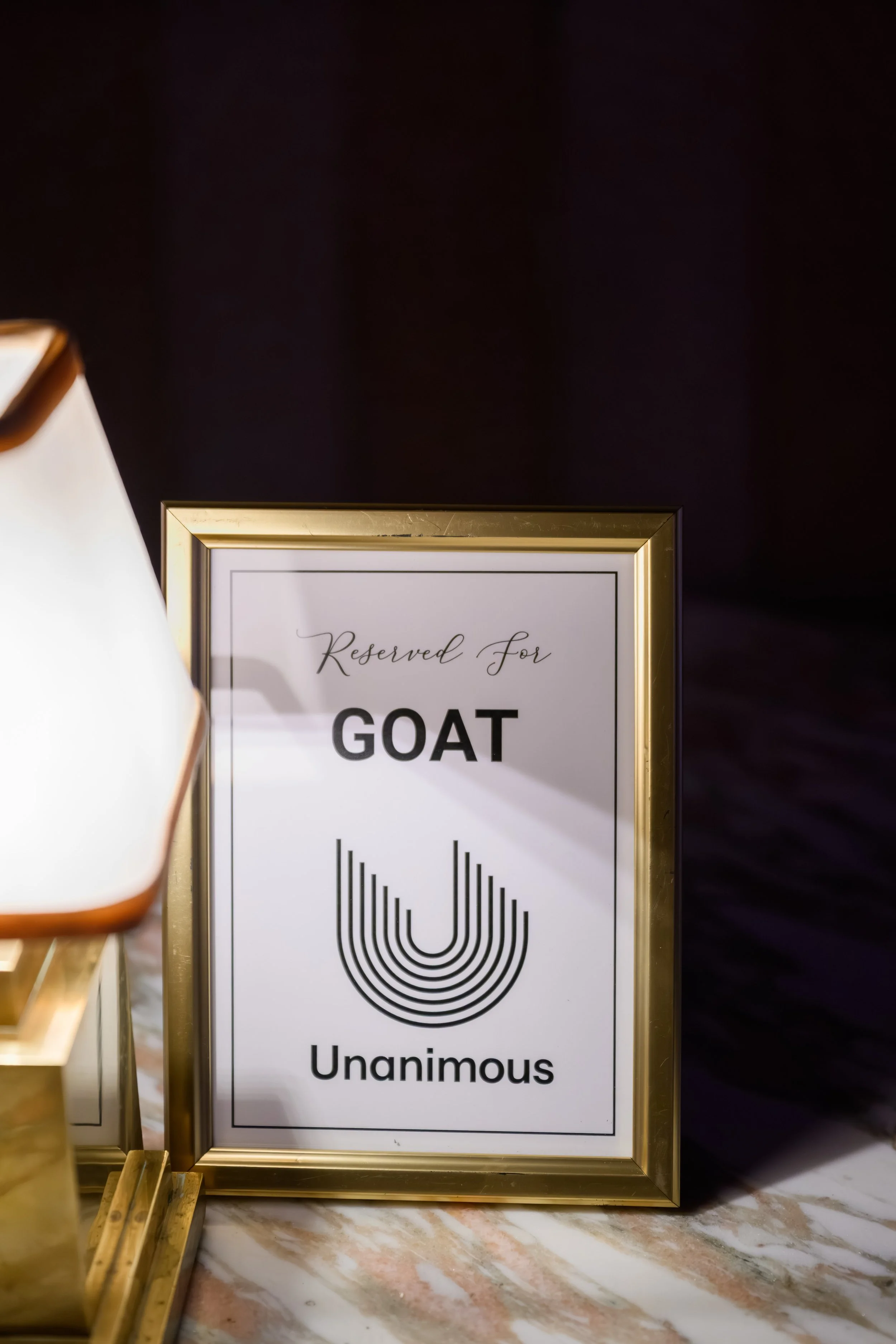 Custom “Reserved for GOAT” tabletop signage featuring Unanimous branding and elevated event styling details during Stephen Curry’s NBA All-Star Weekend rooftop experience produced by Loriann Serna and The Wife of the Party.