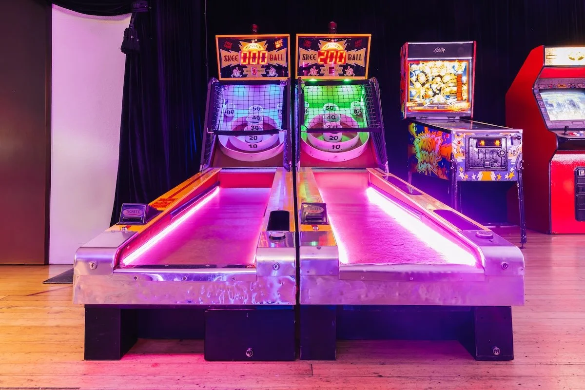 Neon arcade game setup with air hockey table and basketball shooting game at luxury teen gaming birthday party designed by Wife of the Party
