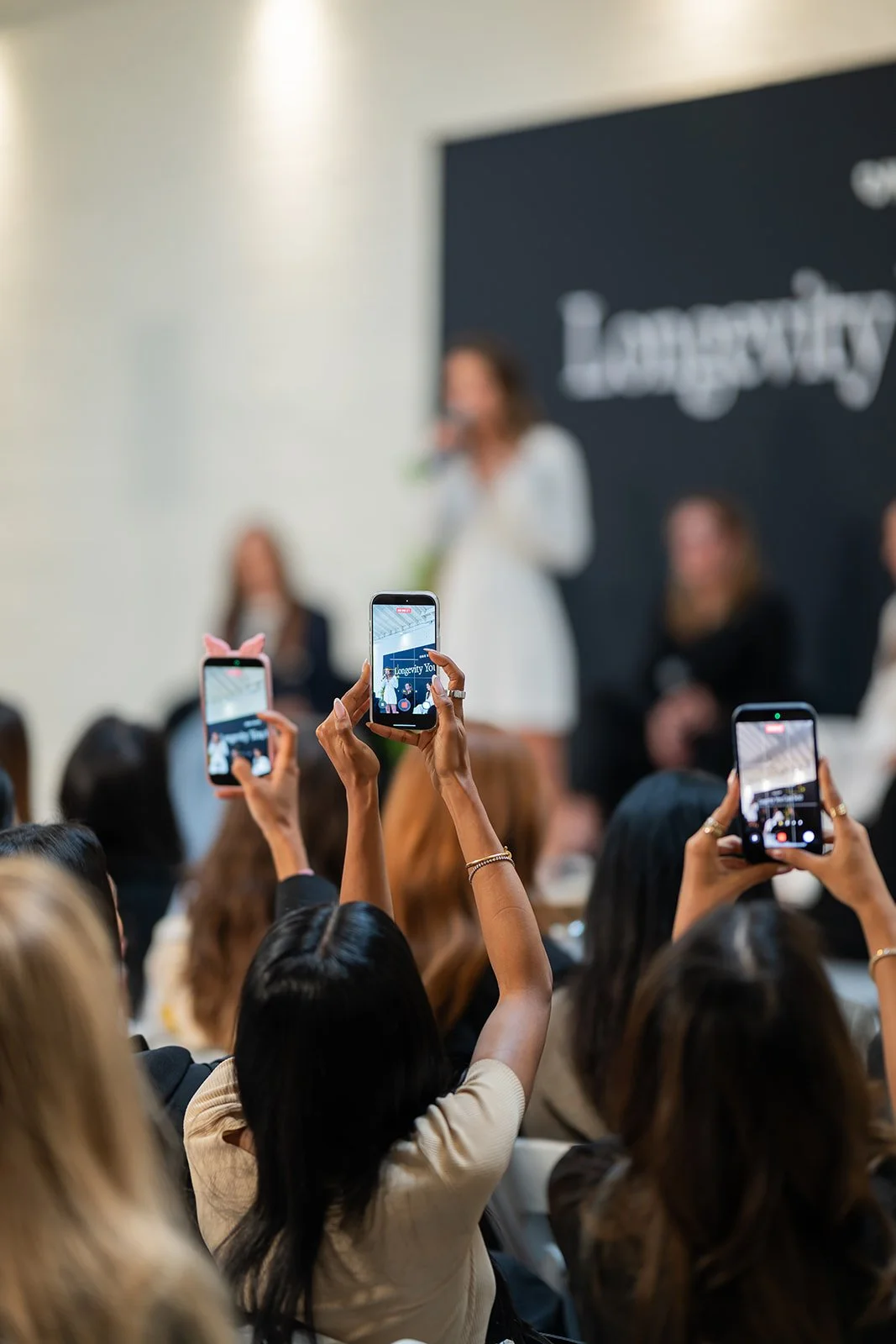 Guests filming panel discussion at OneSkin influencer event with live audience engagement