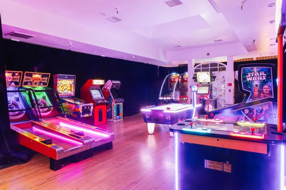 Neon arcade game setup with air hockey table and basketball shooting game at luxury teen gaming birthday party designed by Wife of the Party