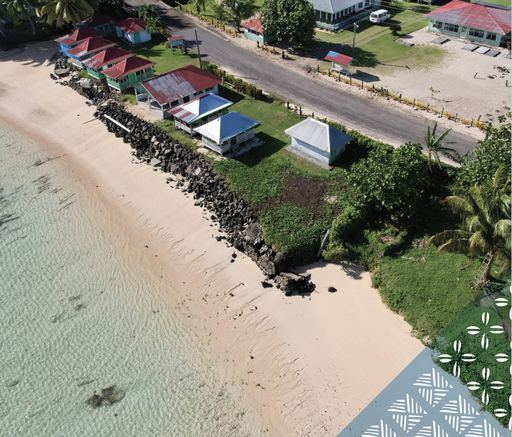 Aerial view of coastal protection works beside homes on a Pacific island coastline.