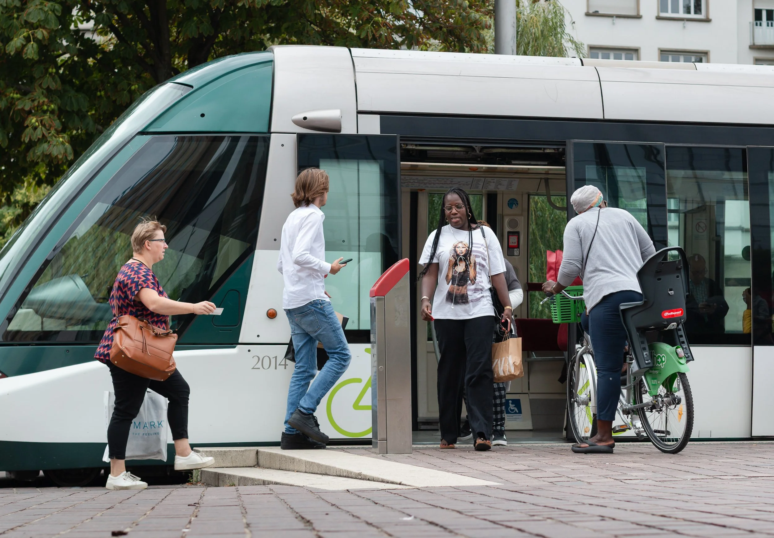 Cyclist standing with a bicycle beside an open tram door in Strasbourg.