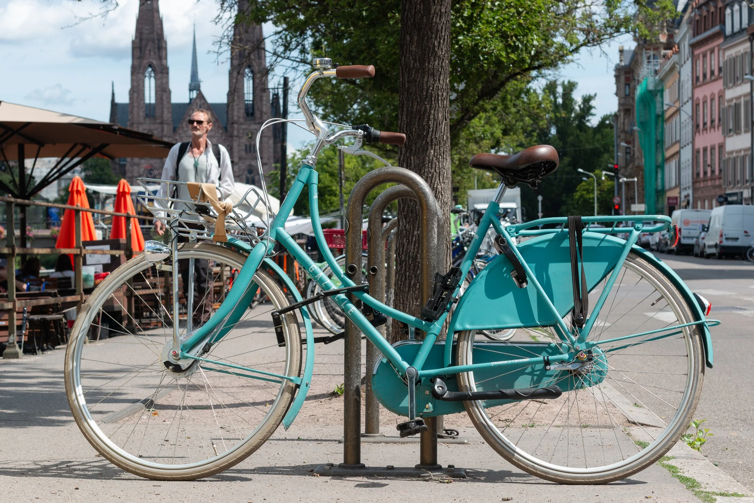 Turquoise bicycle locked to a street rack in central Strasbourg.