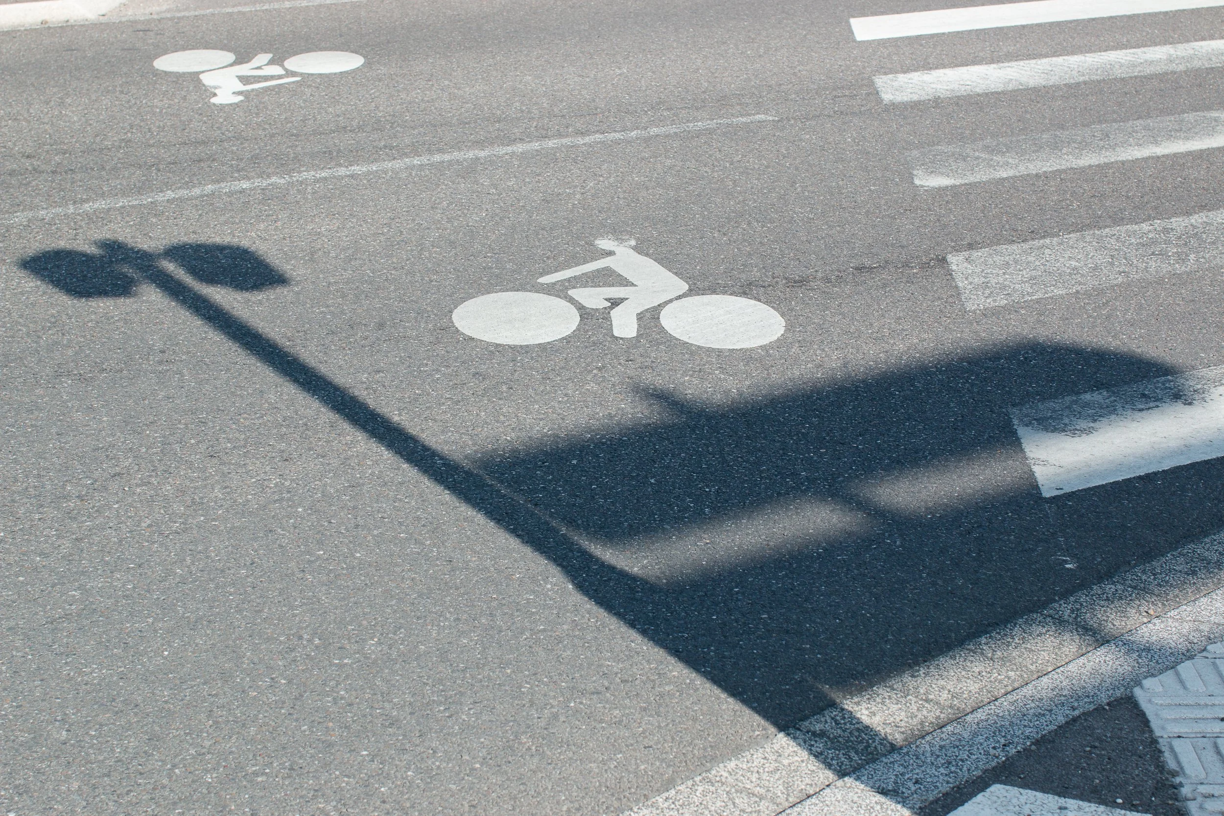 Bicycle lane markings and the shadow of a streetlamp on a Strasbourg road.