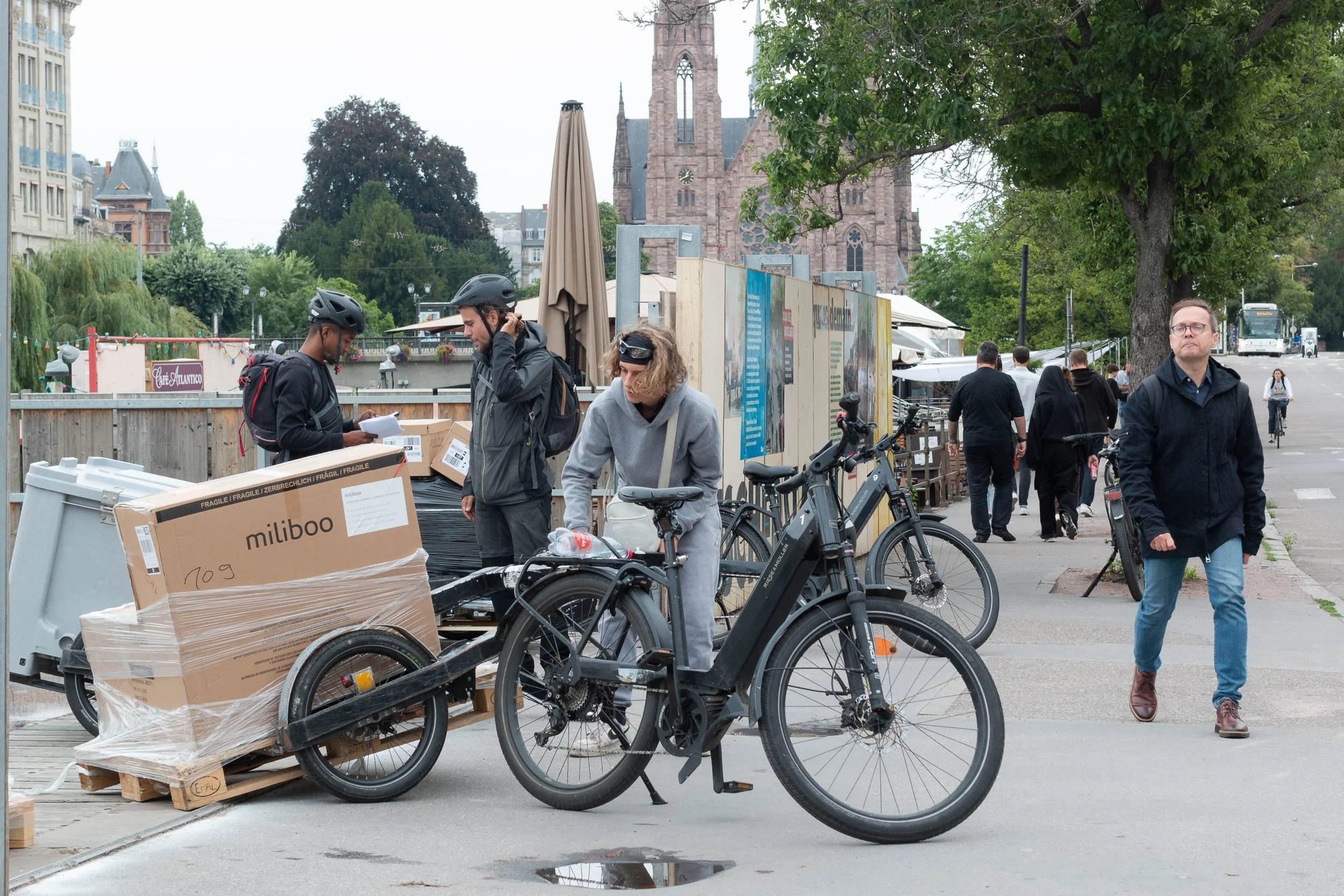 Cargo bicycle loaded with large boxes on a busy Strasbourg street.