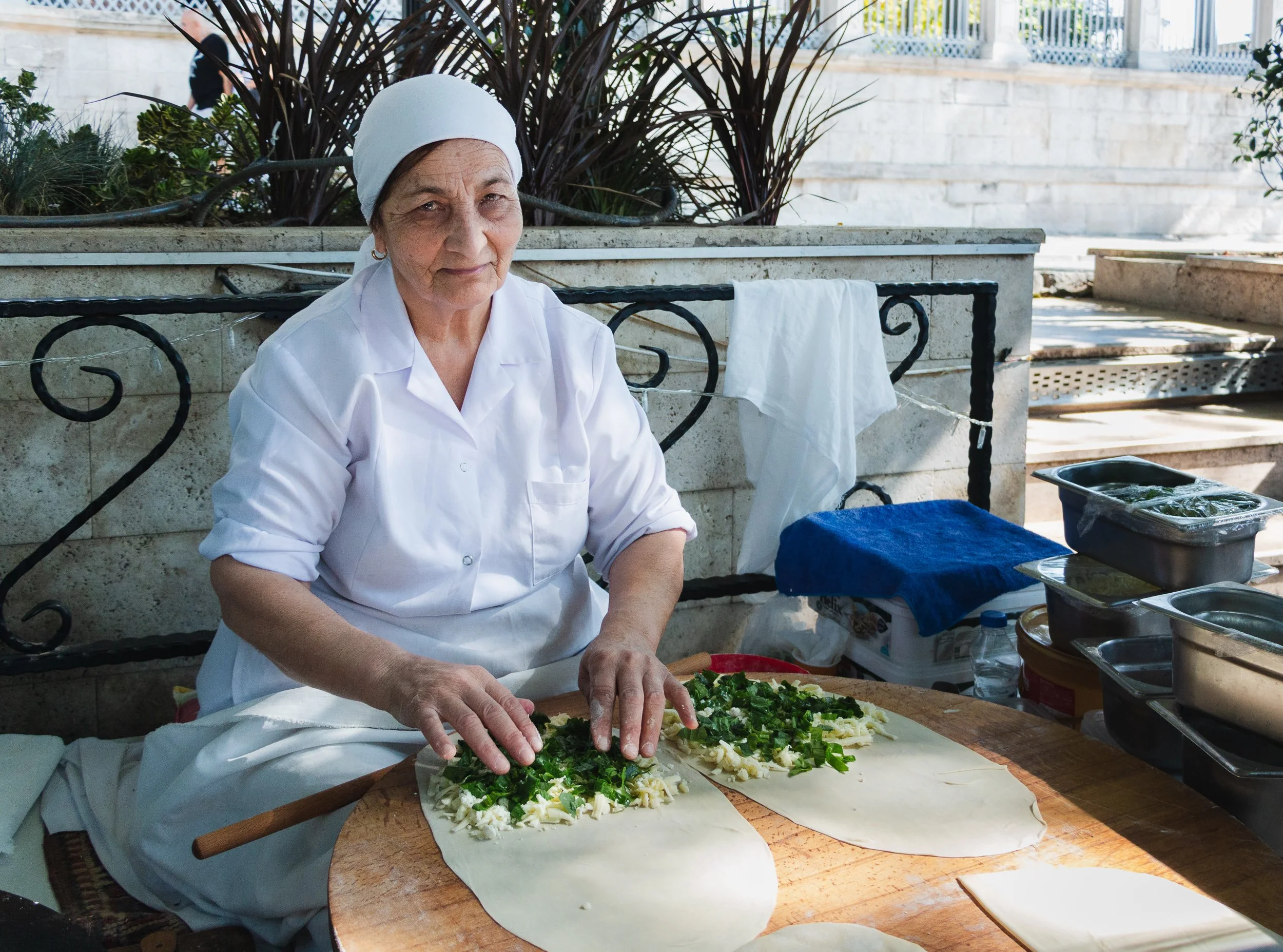 Woman preparing flatbread with fresh herbs at an outdoor food station in Istanbul.