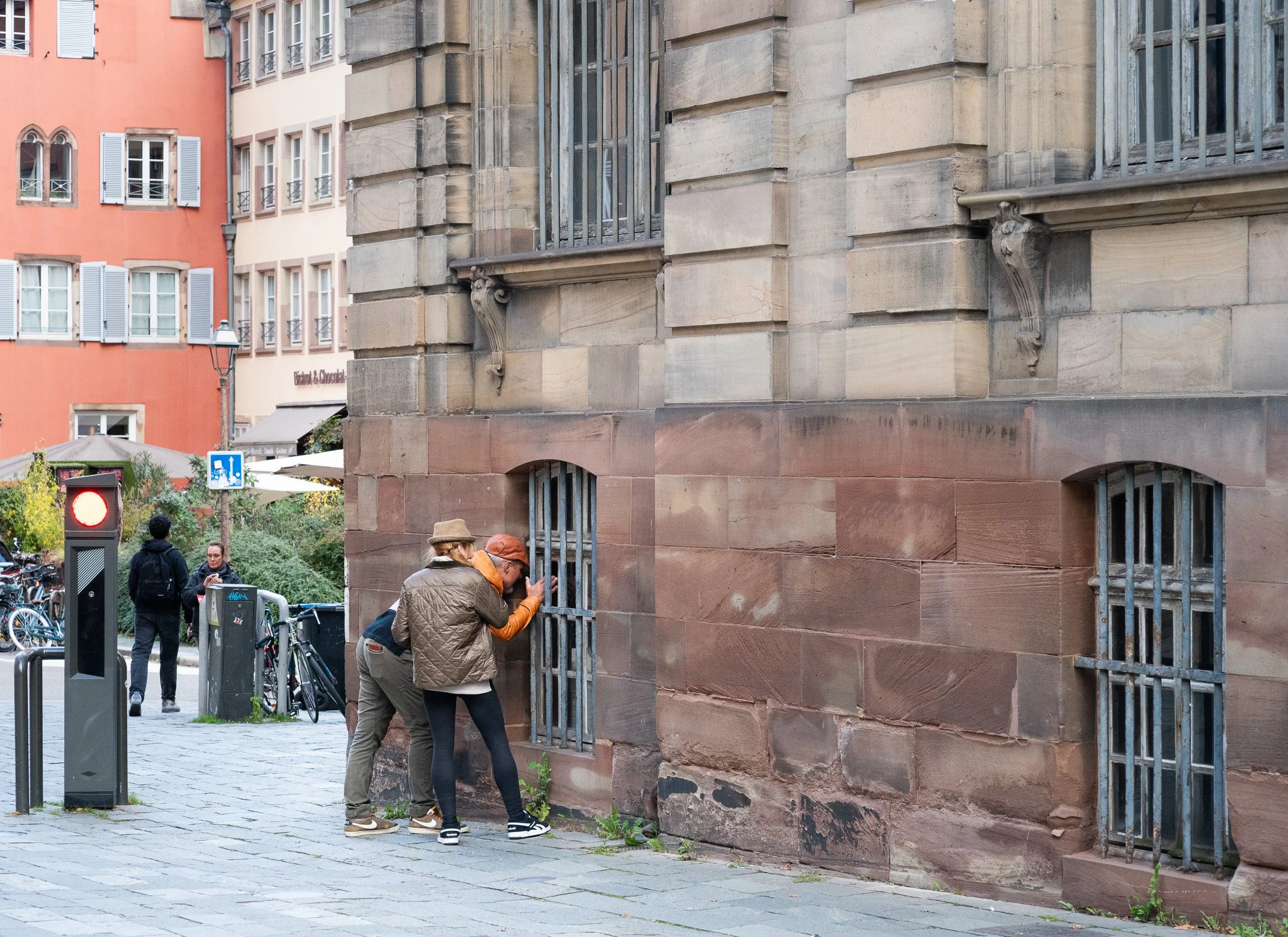 Two people looking through the barred window of a historic building.