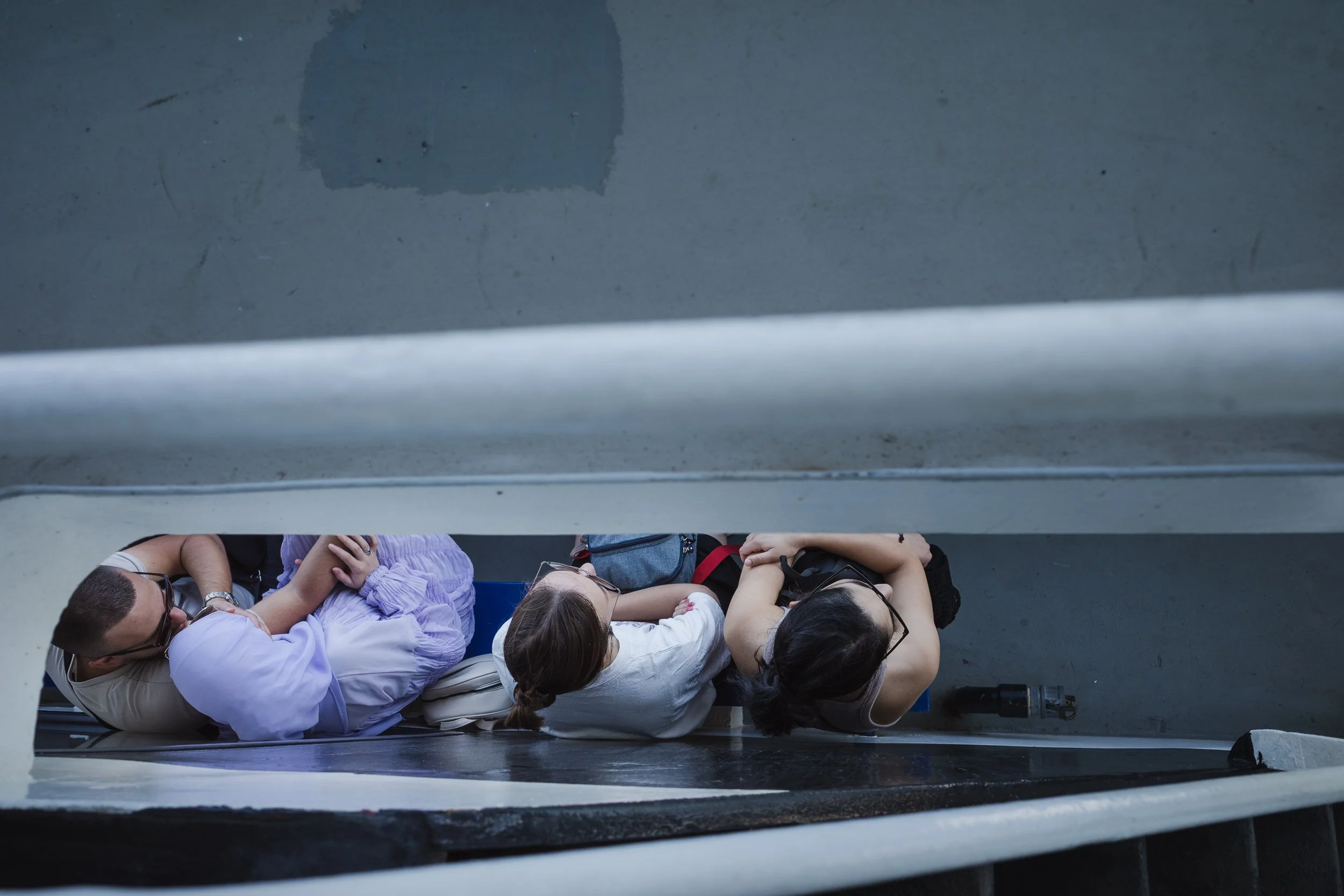 Ferry passengers seen from above through a narrow opening between decks.