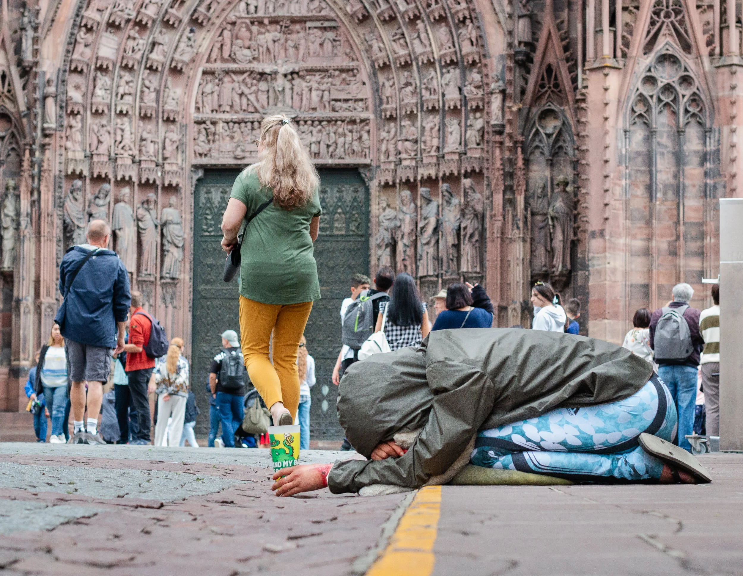Two contrasting figures on the pavement in front of Strasbourg Cathedral.