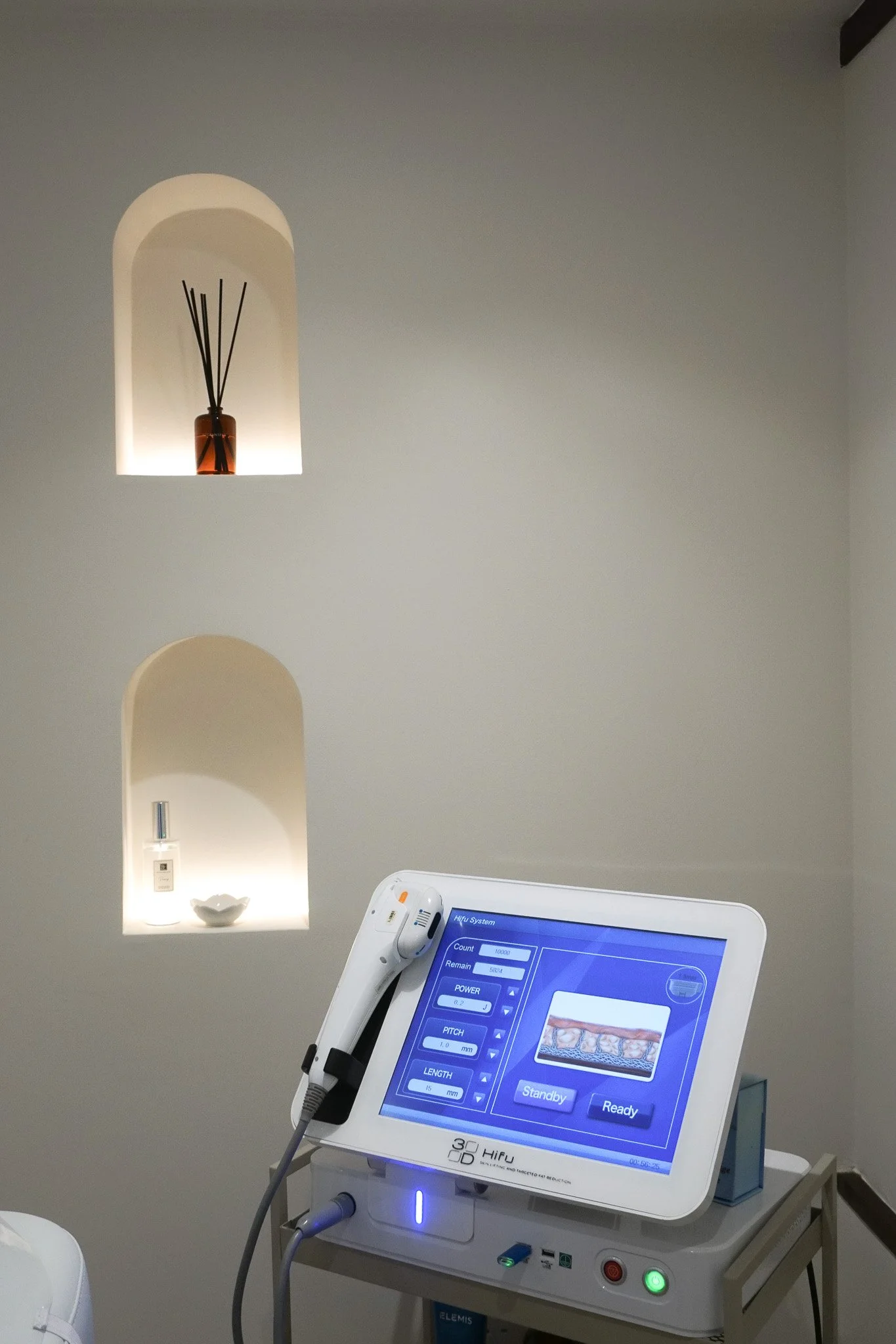 Medical device with a touchscreen display showing controls and information, connected to a flexible arm, in a clinical setting.