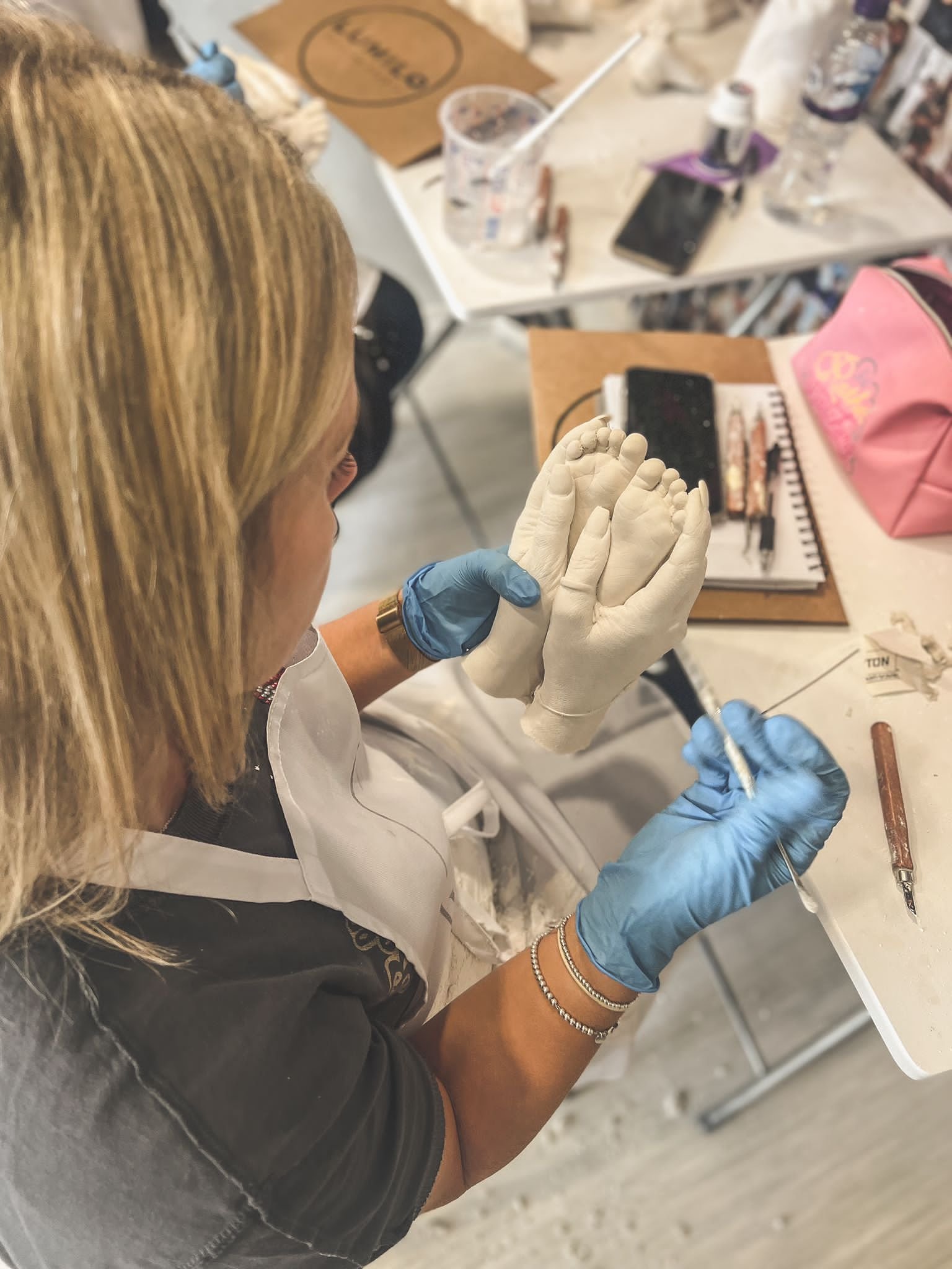 Person sculpting a plaster hand model at a table with art supplies.