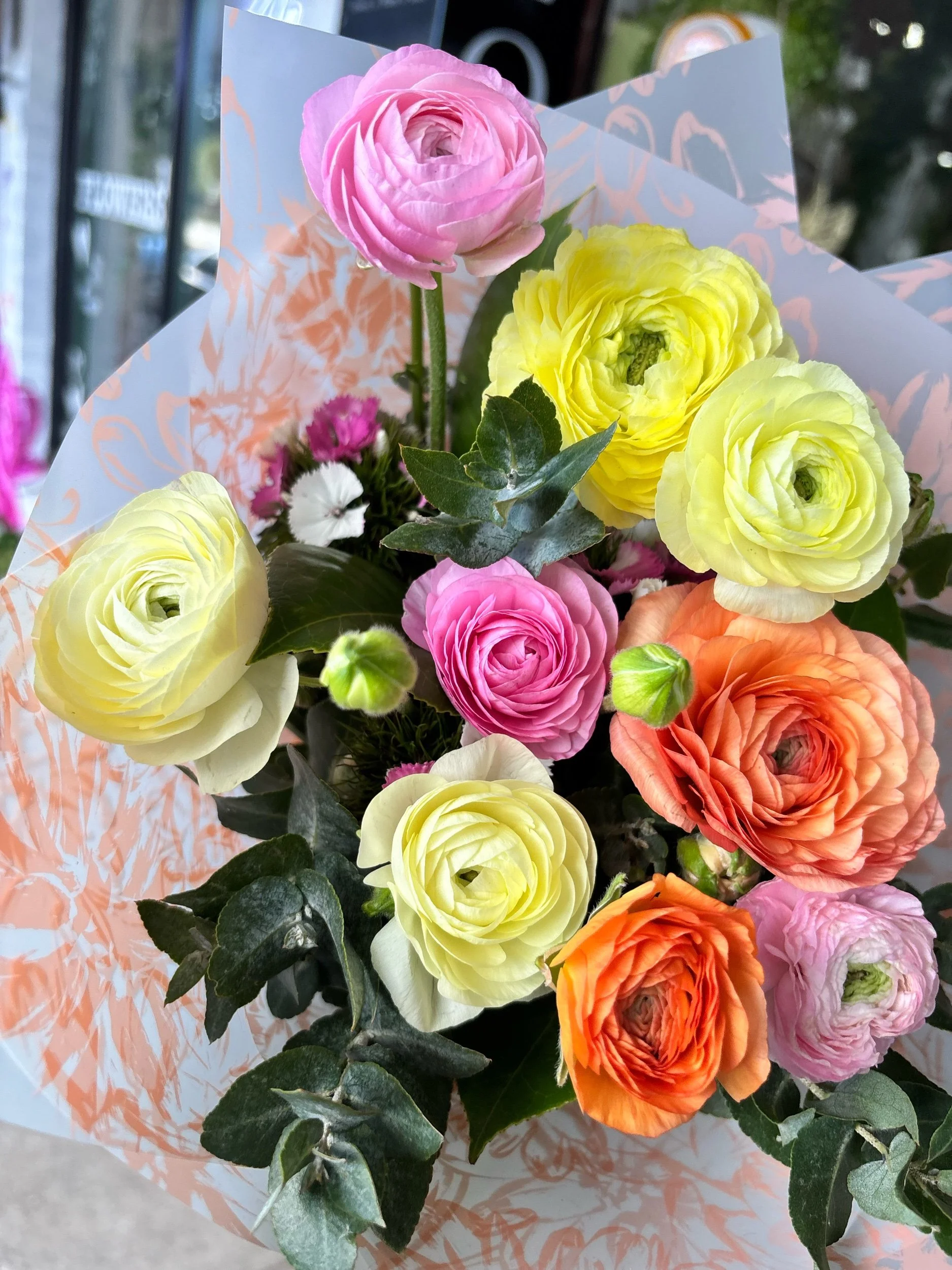 A bouquet of pastel pink, peach and lemon Ranunculas.