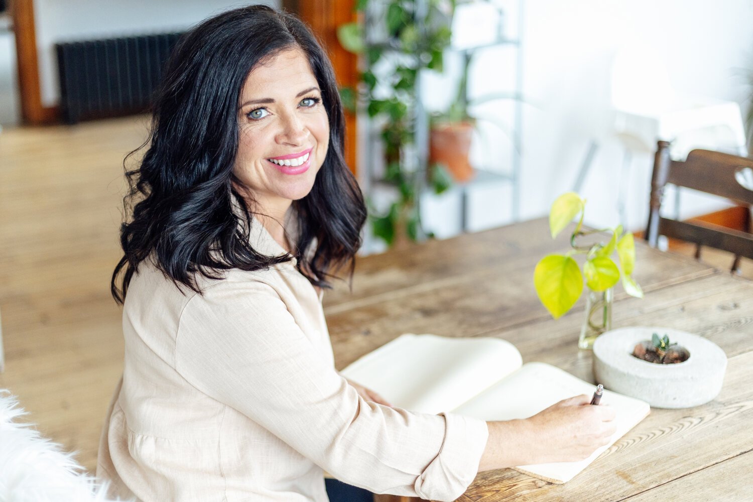 Charmaine Renee, rest coach and breathwork practitioner, sitting at a wooden table.