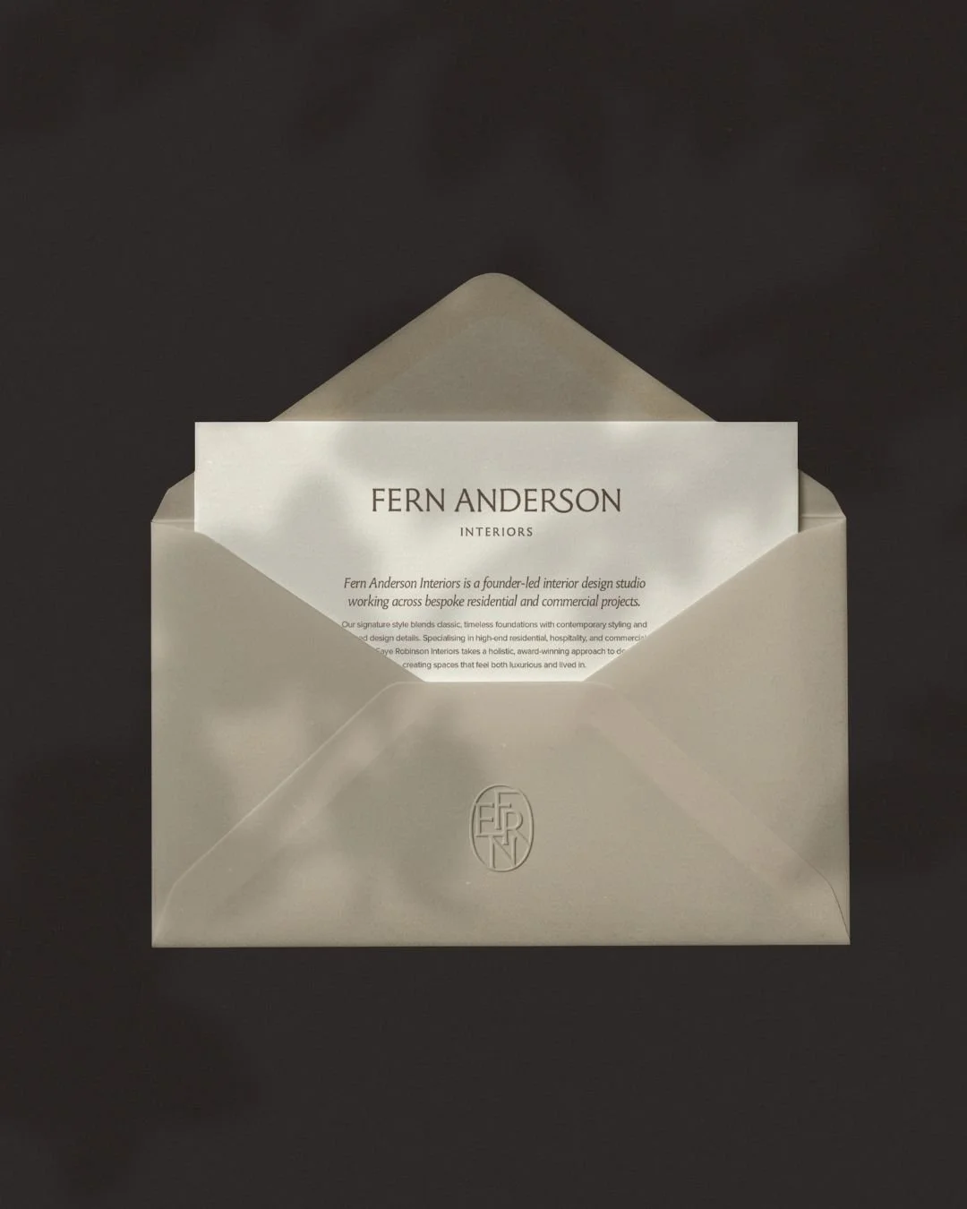 Fern Anderson Interiors brand stationery, the studio wordmark printed on a personalised welcome card emerging from a charcoal envelope, designed by The Brand Muse.