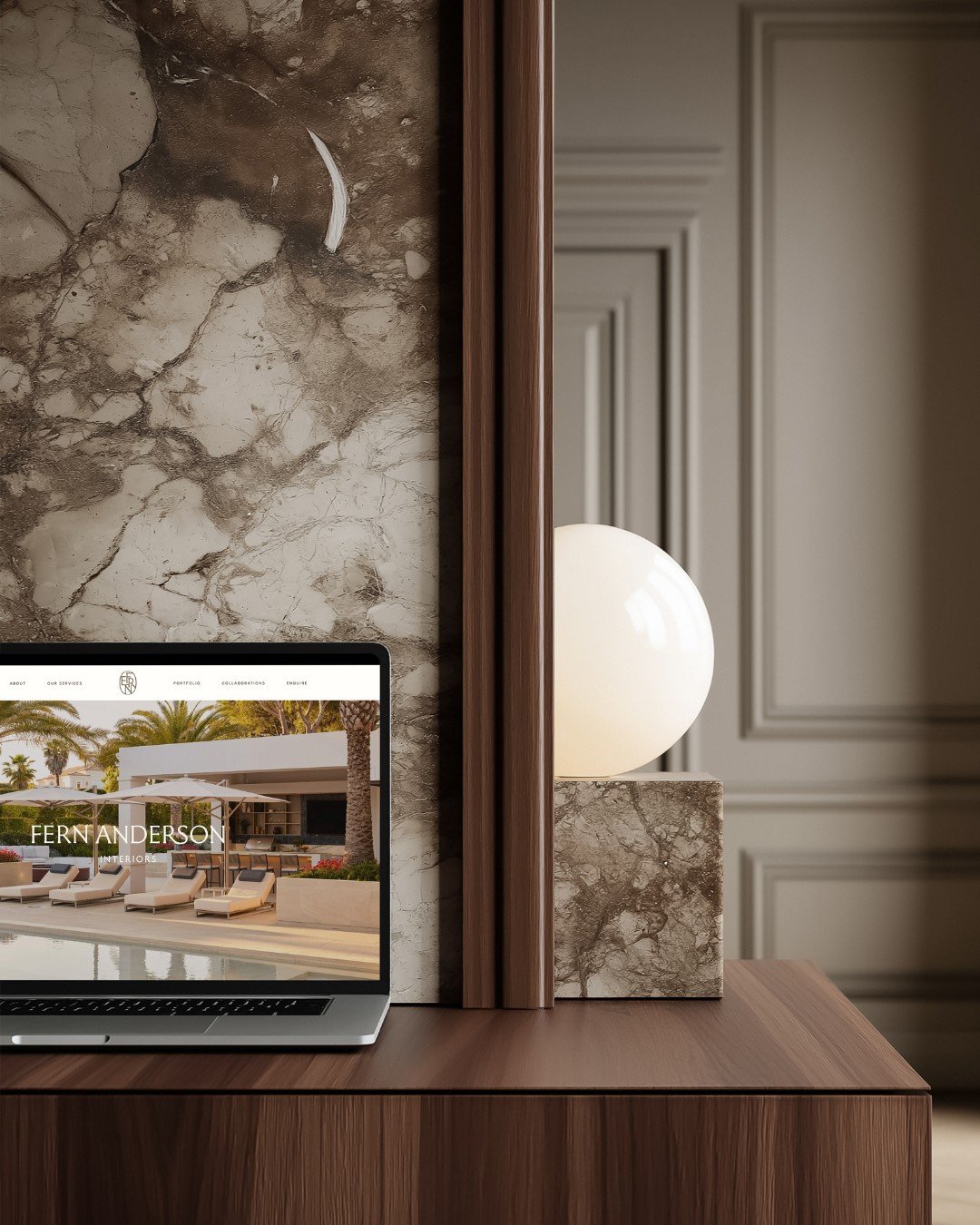 Fern Anderson Interiors website preview displayed on a laptop in a styled brand still life with a marble sphere lamp and warm wood surfaces, designed by The Brand Muse.