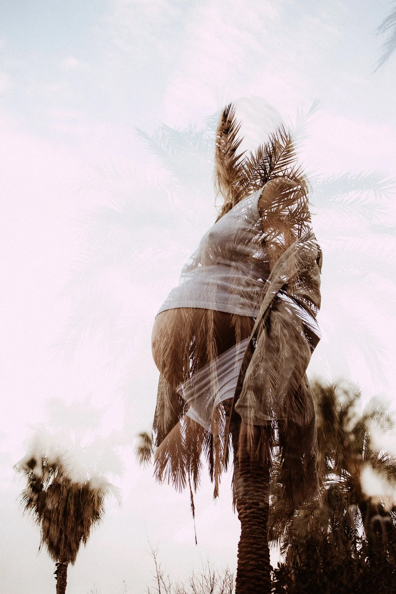 A double exposure photograph showing a pregnant woman and palm trees against a cloudy sky.