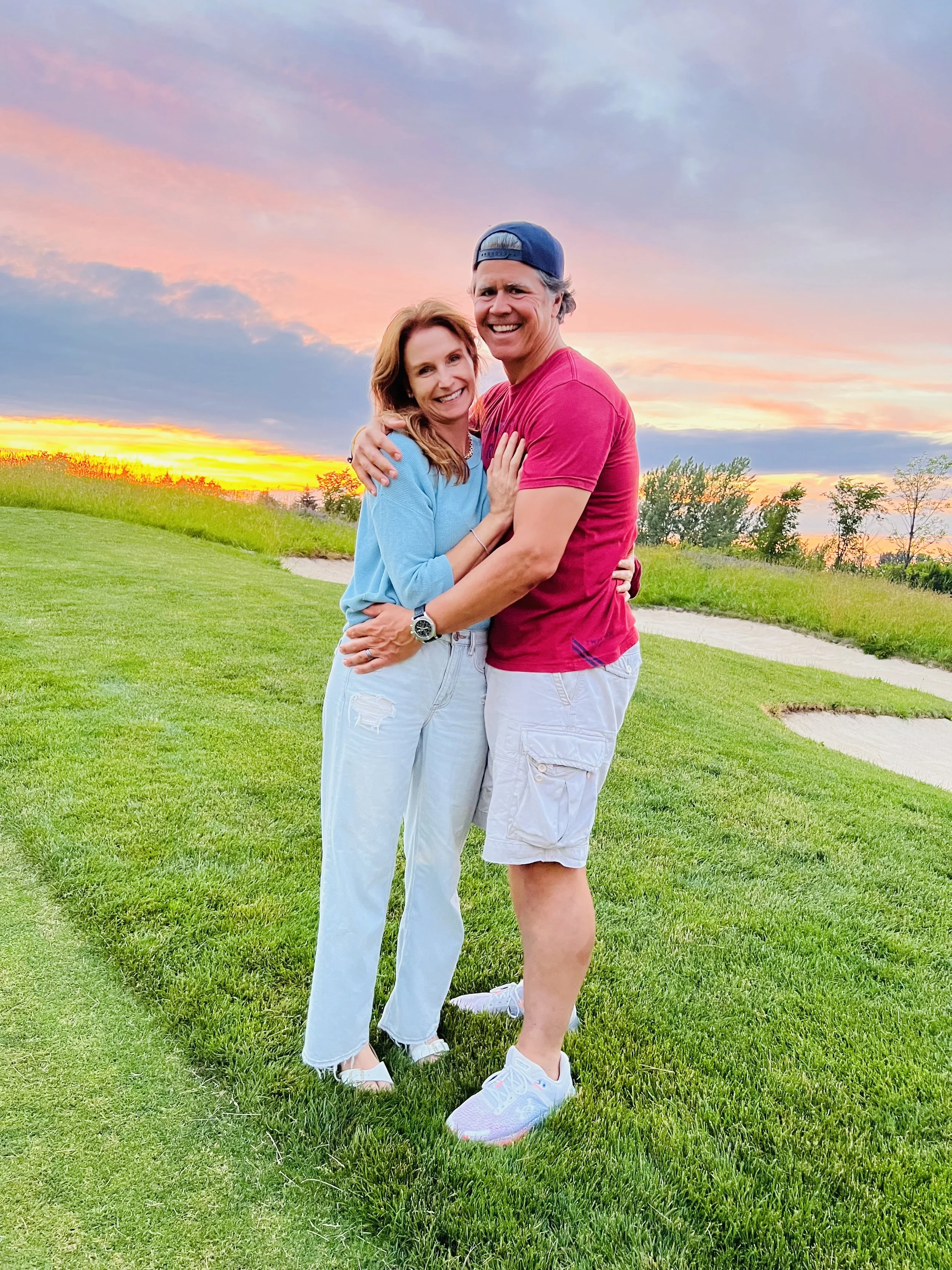 a couple embracing in the grass at sunset