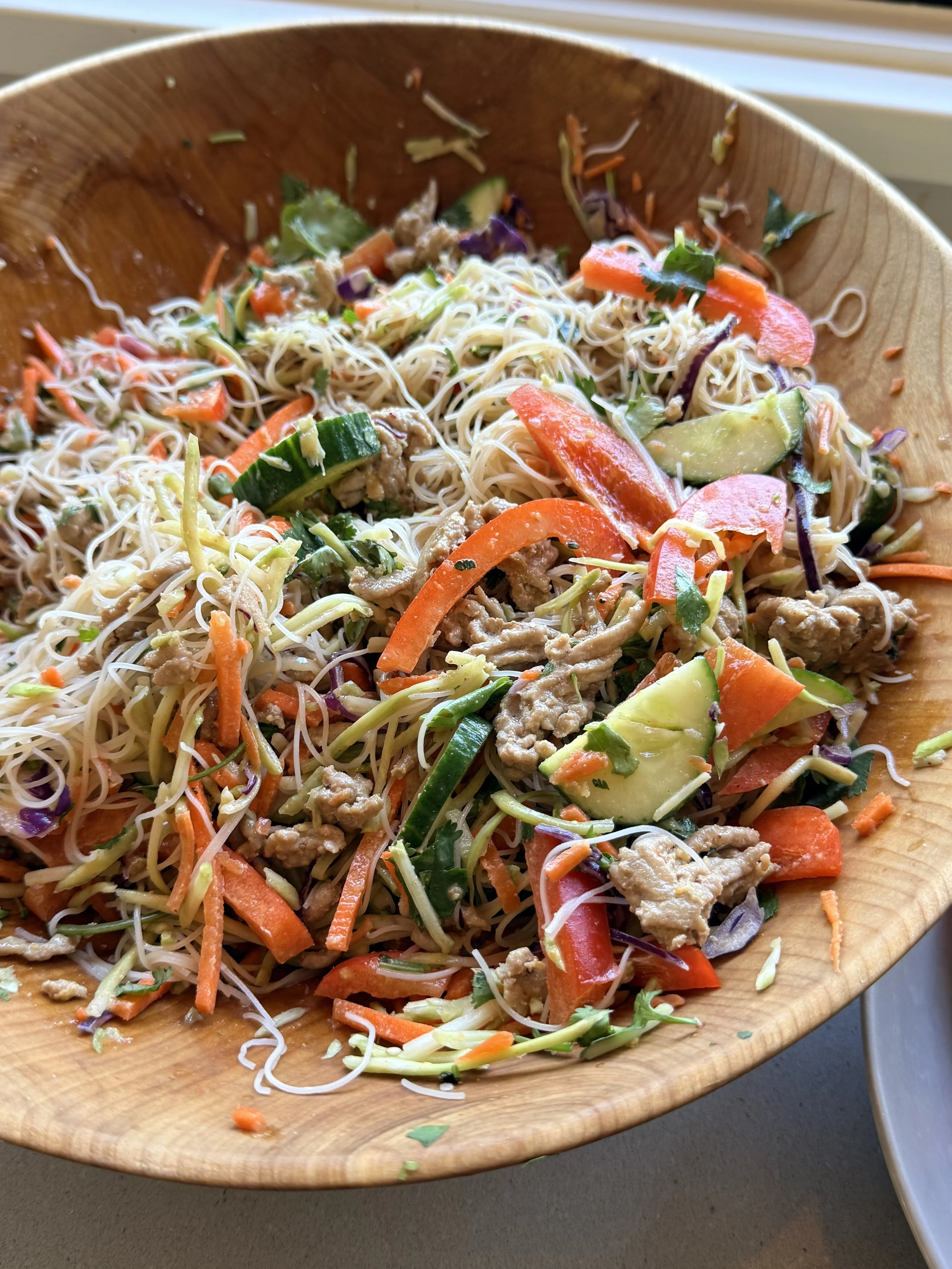 Asian Rice Noodle Salad in wooden bowl by window