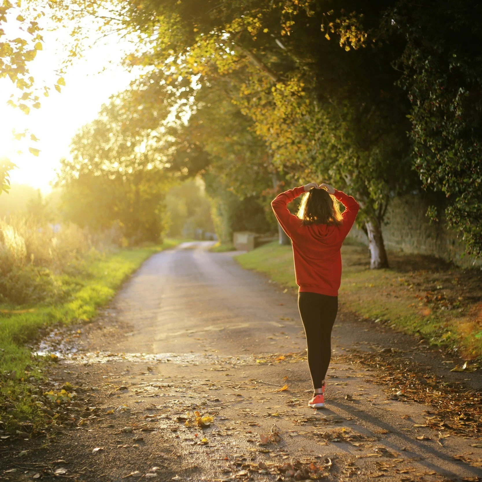 woman in red jacket walking at sunrise on a quiet road