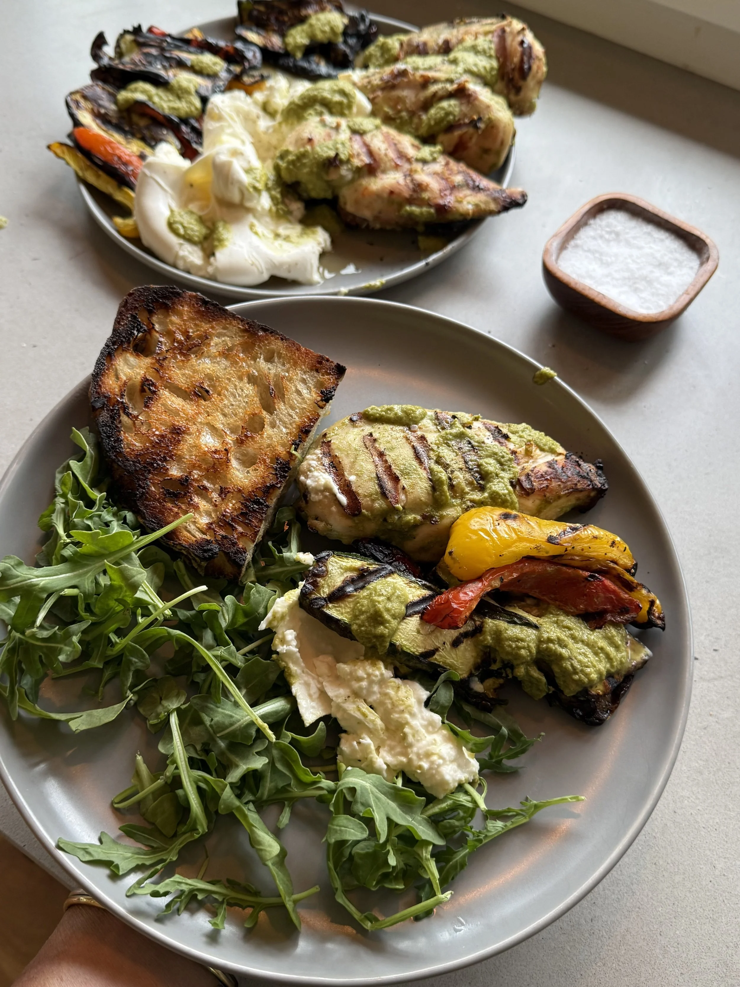 grilled chicken breast, bbq veggies, burrata and toasted sourdough on a grey plate