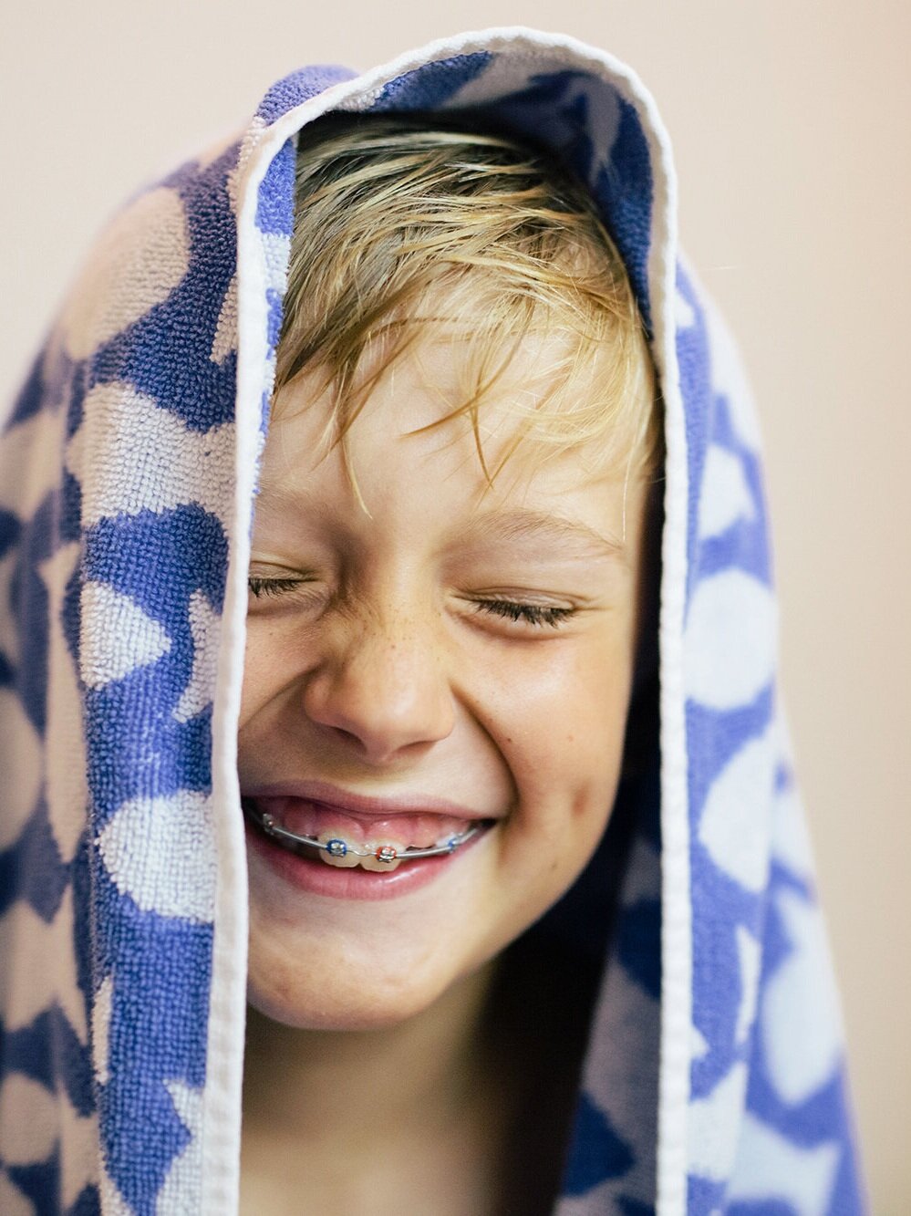 Bambino felice e sorridente, avvolto in un telo da bagno