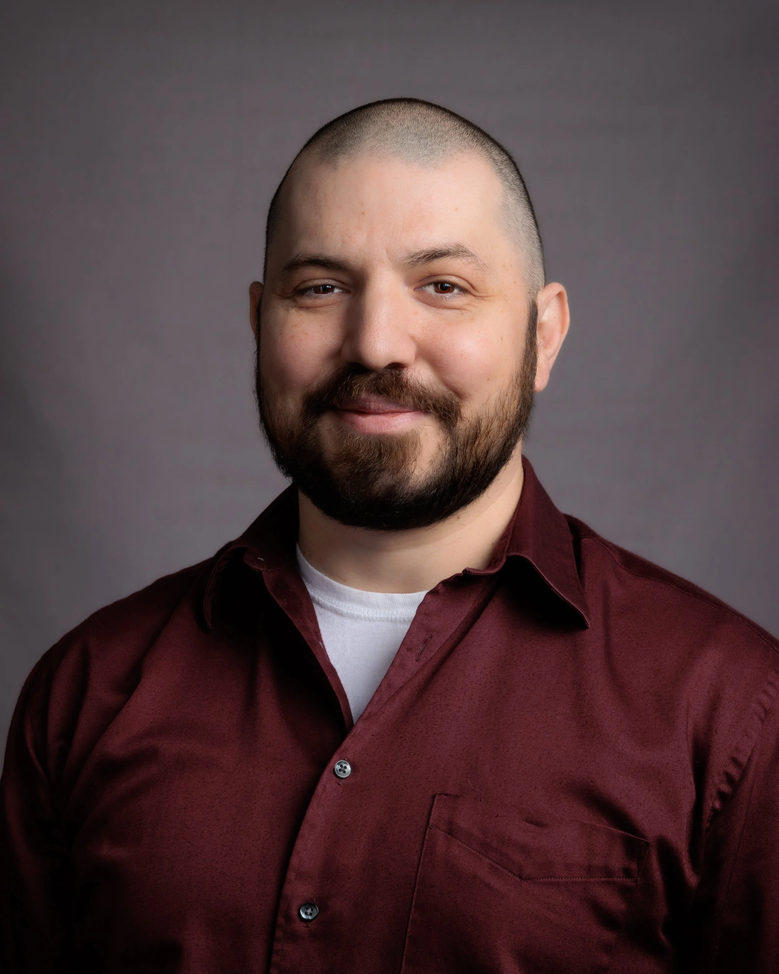 A man with a beard and mustache wearing a red button down shirt.