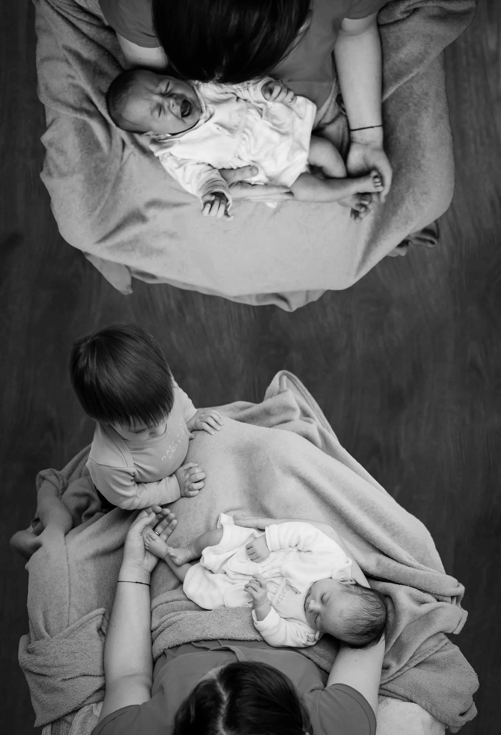 b/w image of twin newborns being held by parents